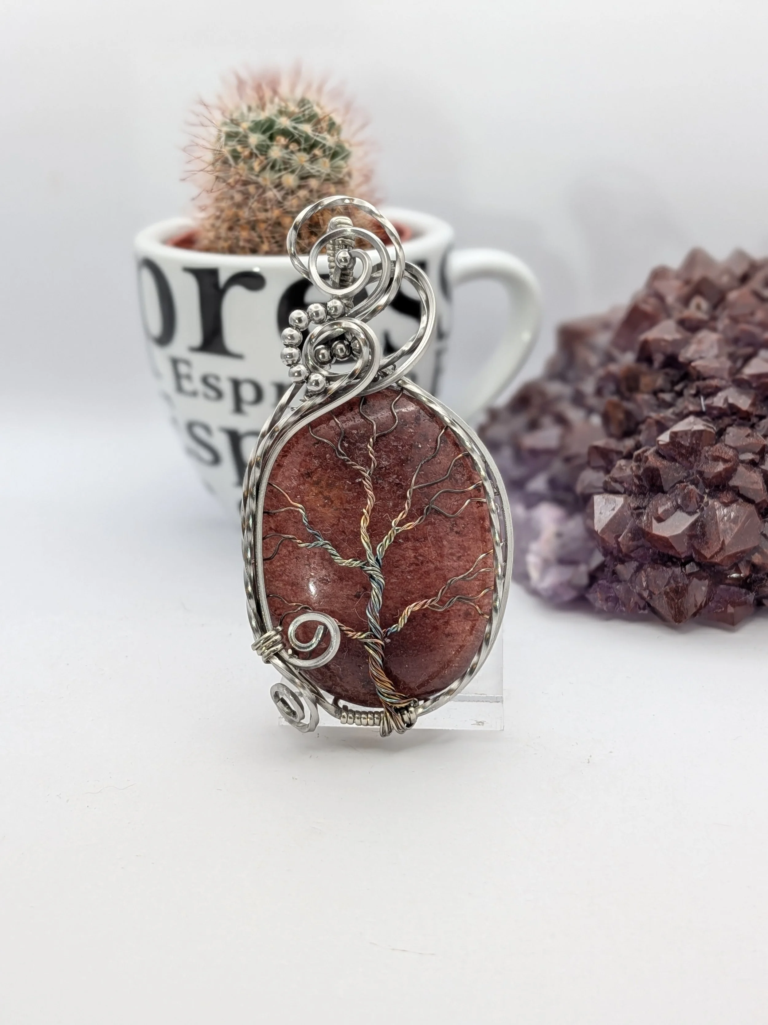 This captivating, stainless wire Strawberry Quartz tree of life pendant draws you into a stunning forest. Featuring a clean background, this piece offers a beautiful, detailed view on both sides.