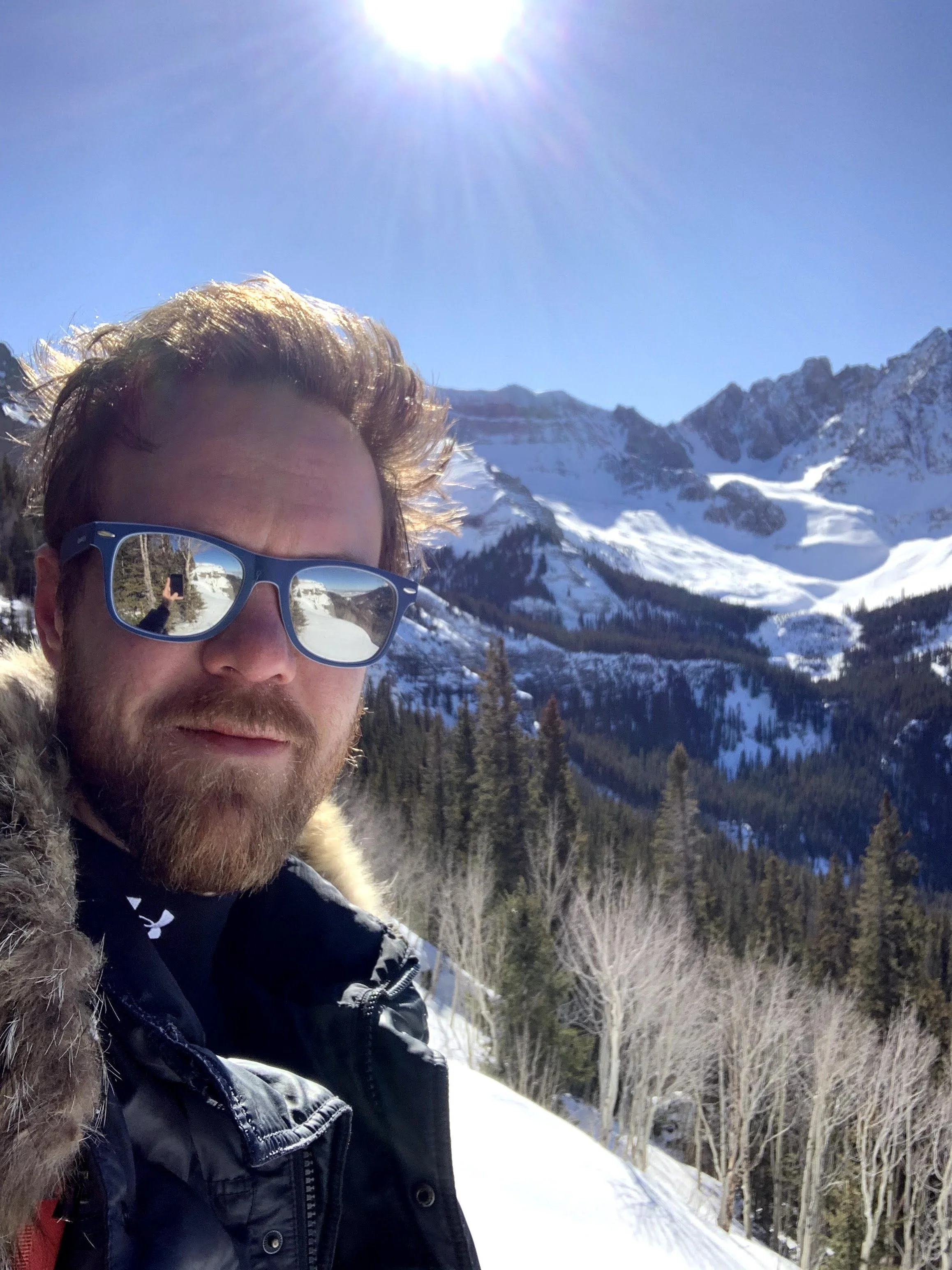 Criminal appeals attorney with sunglasses taking a selfie in a snowy mountain landscape on a sunny day.