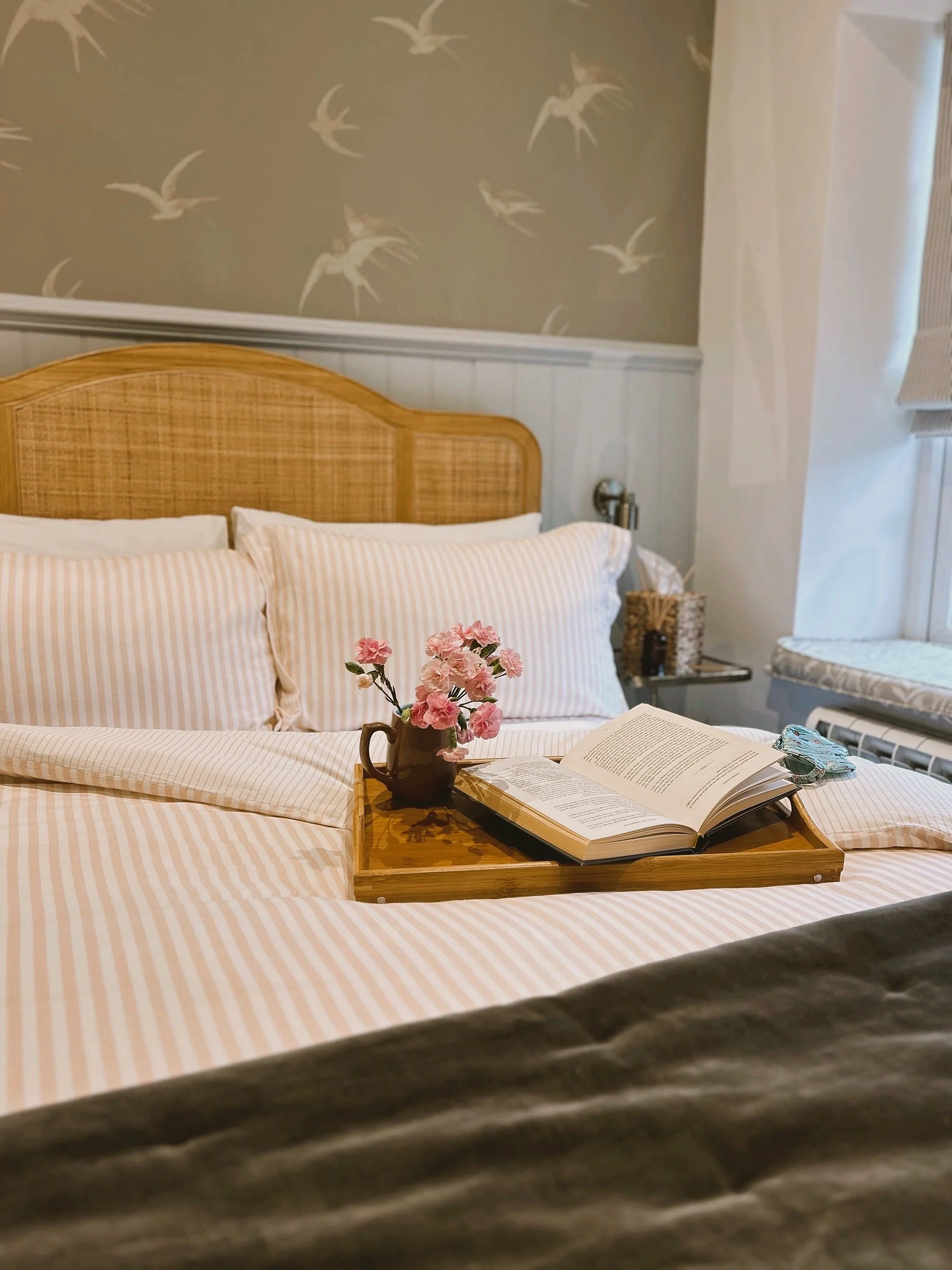 Rattan headboard against wall with bird wallpaper pattern.