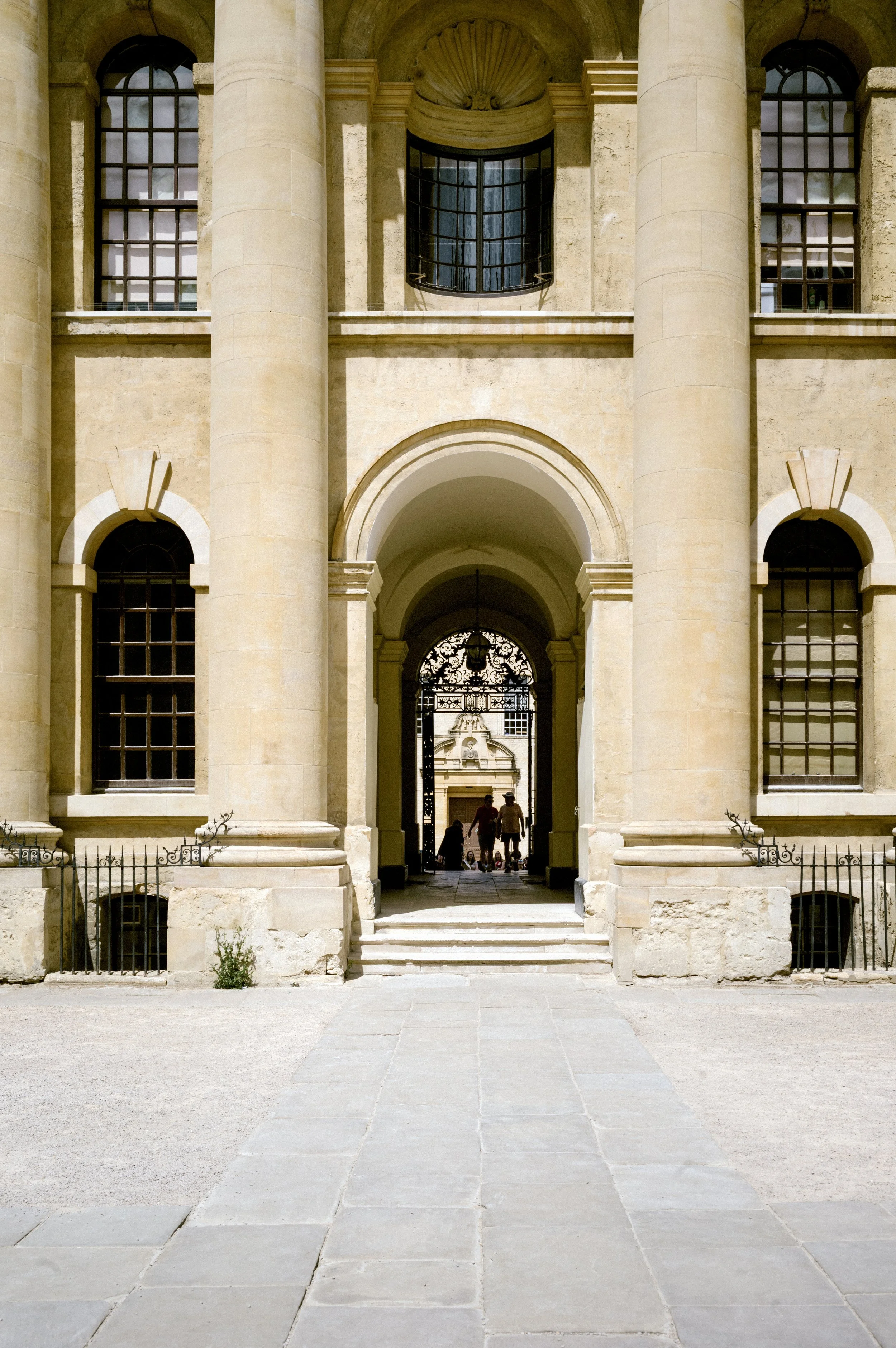 Stone archway and columns of the Clarendon Building in Oxford framing an ironwork gate