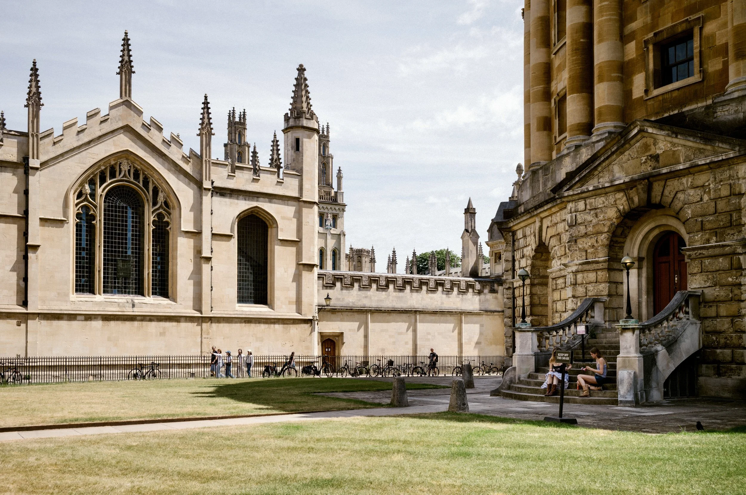 Gothic twin towers of All Souls College, Oxford University, above a striped lawn and blue sky