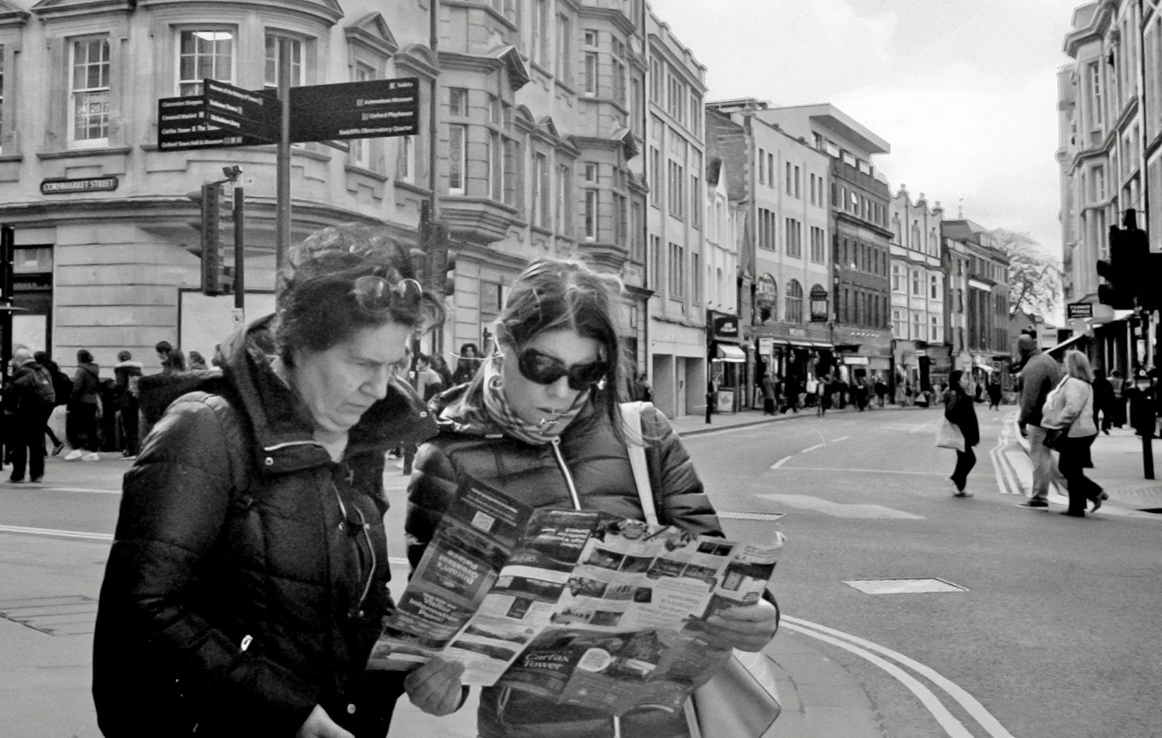 Two tourists reading a city map on a busy Oxford street, captured on a Leica M6 using Ilford HP5 Plus film during a street photography walk.