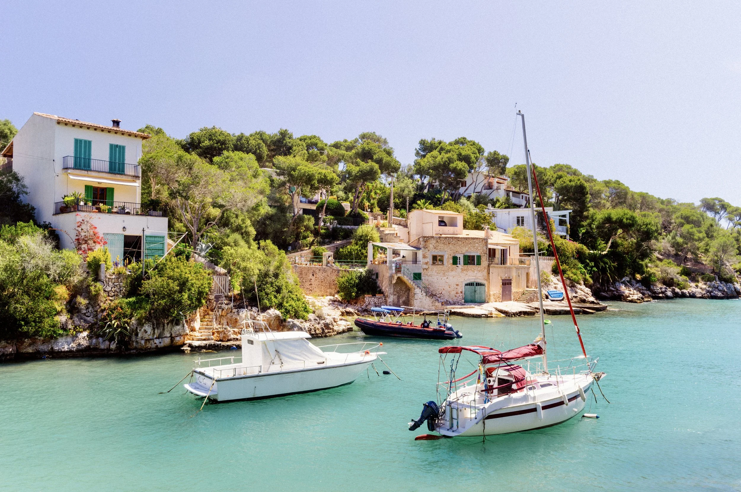 A motorboat and sailing boat moored in the calm turquoise harbour of Cala Figuera, Mallorca