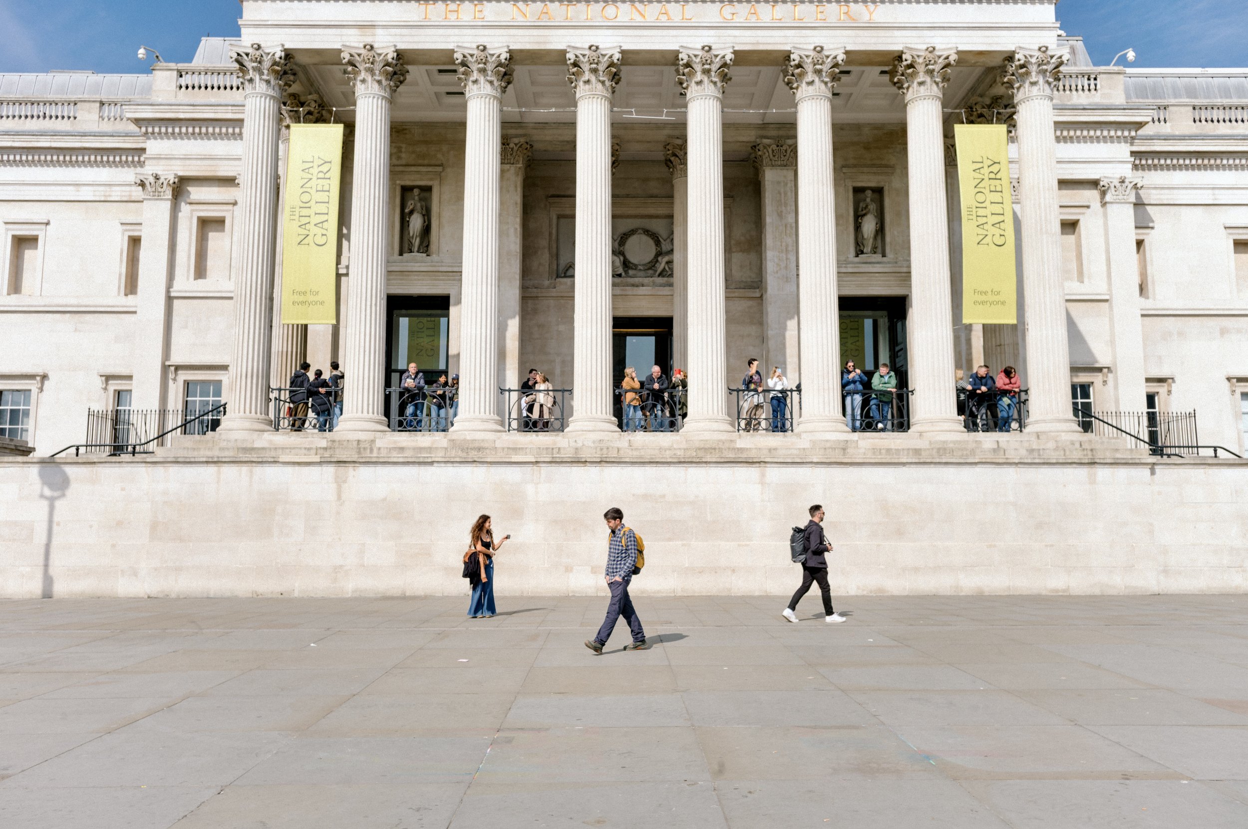 People walking past the front entrance and columns of the National Gallery in Trafalgar Square London.
