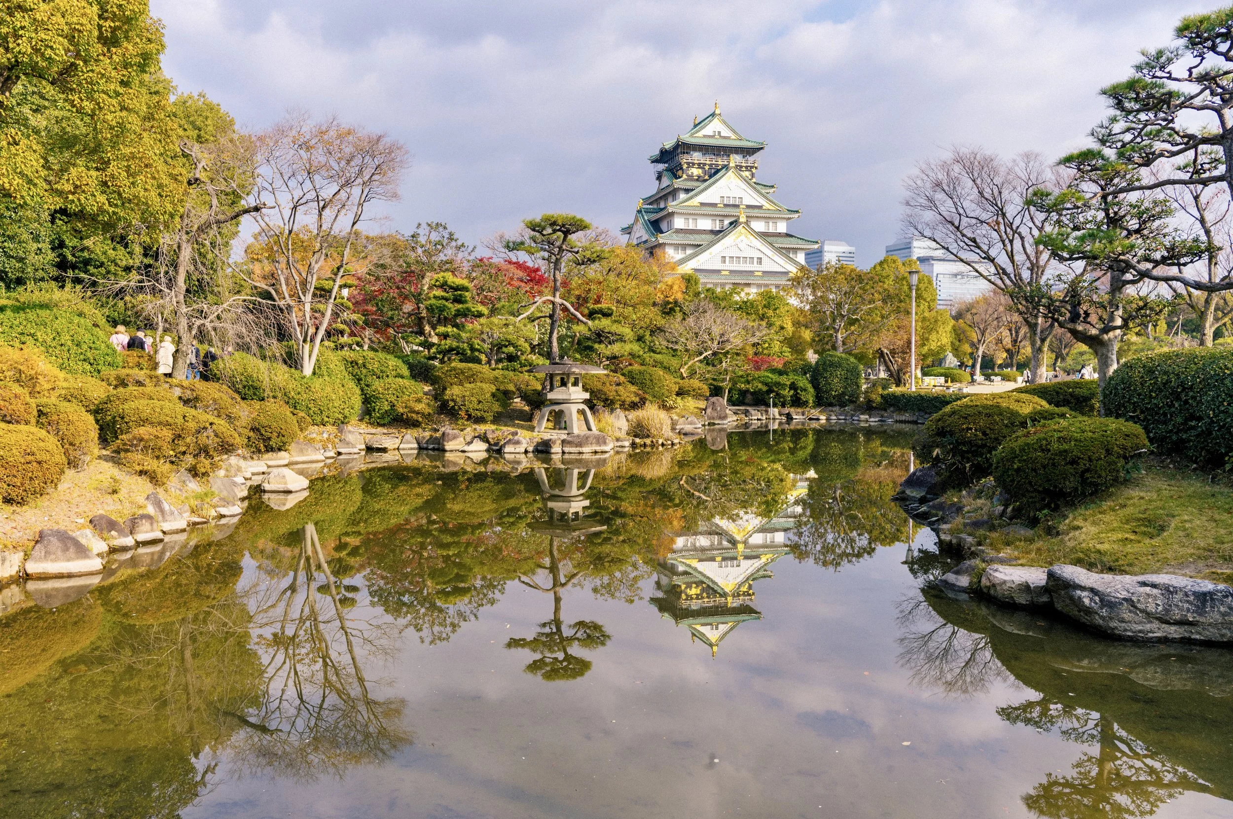 Osaka Castle reflection in pond surrounded by park