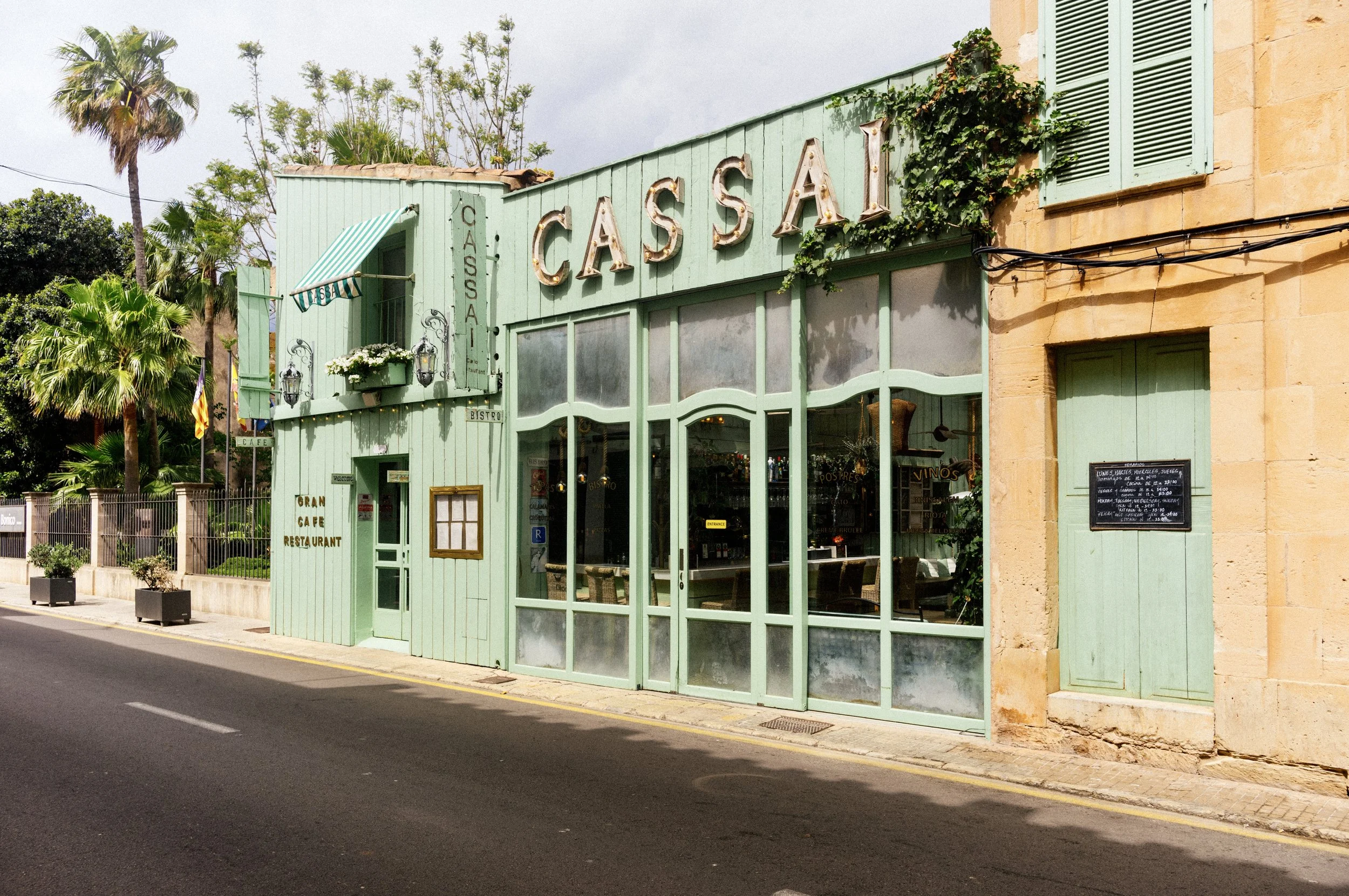 Mint-green facade of the Cassai Gran Café restaurant on a quiet street in Santanyí, Mallorca