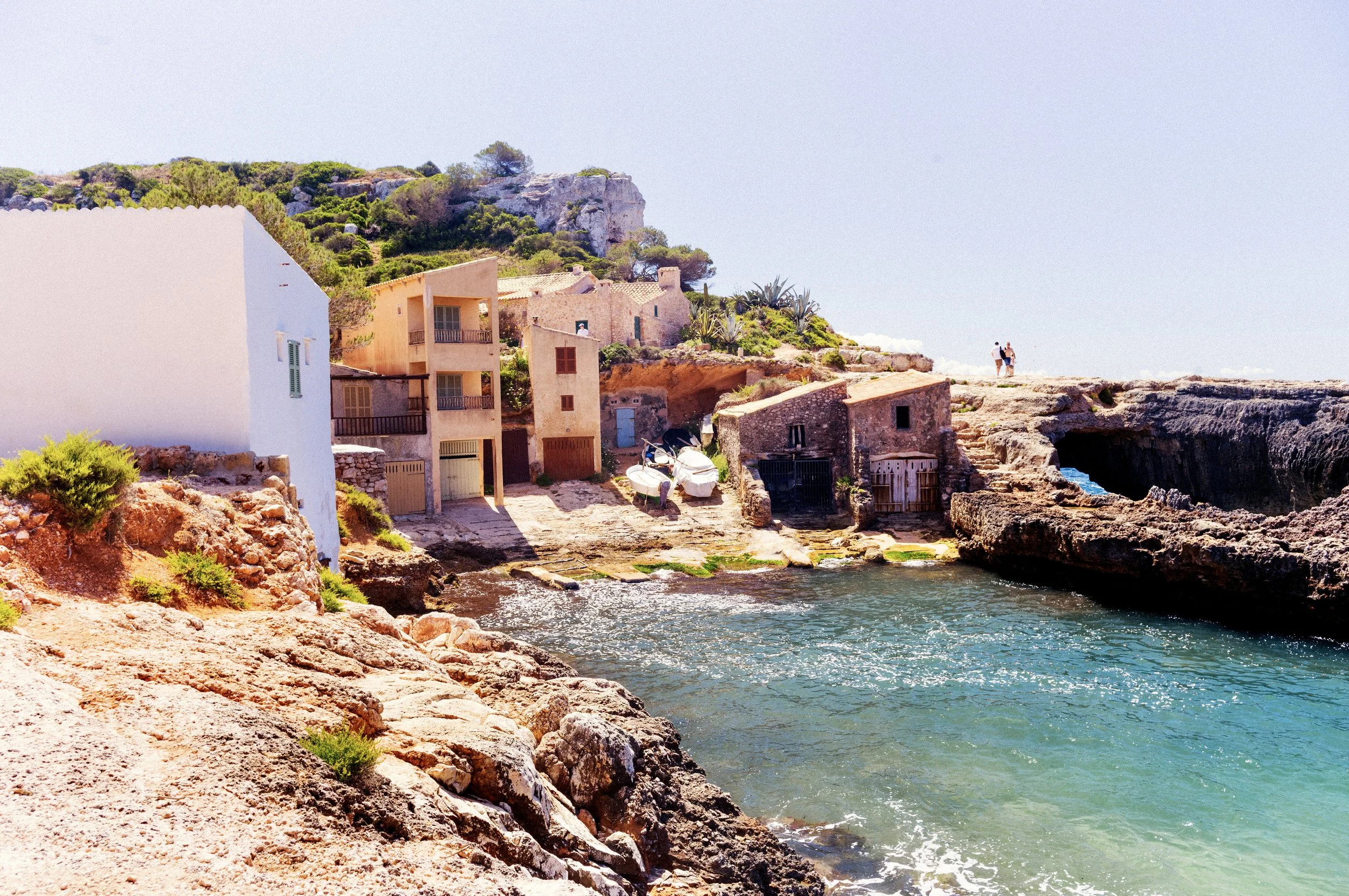 Old stone fishermen's houses and a small boat beside a rocky inlet on the Mallorca coast