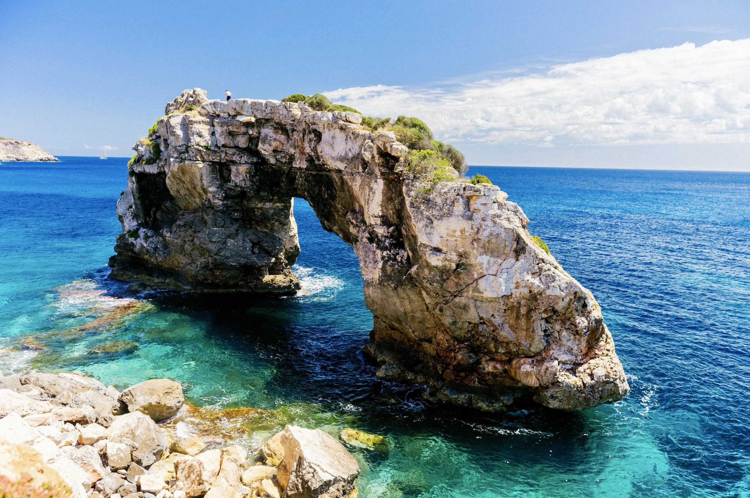 The Es Pontàs natural rock arch rising from deep blue water on Mallorca's south coast