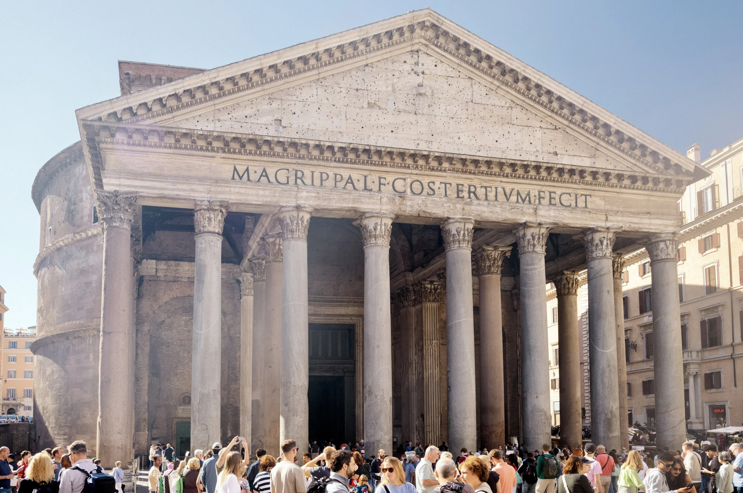The Pantheon façade in Rome with tall Corinthian columns and visitors gathered at the entrance.