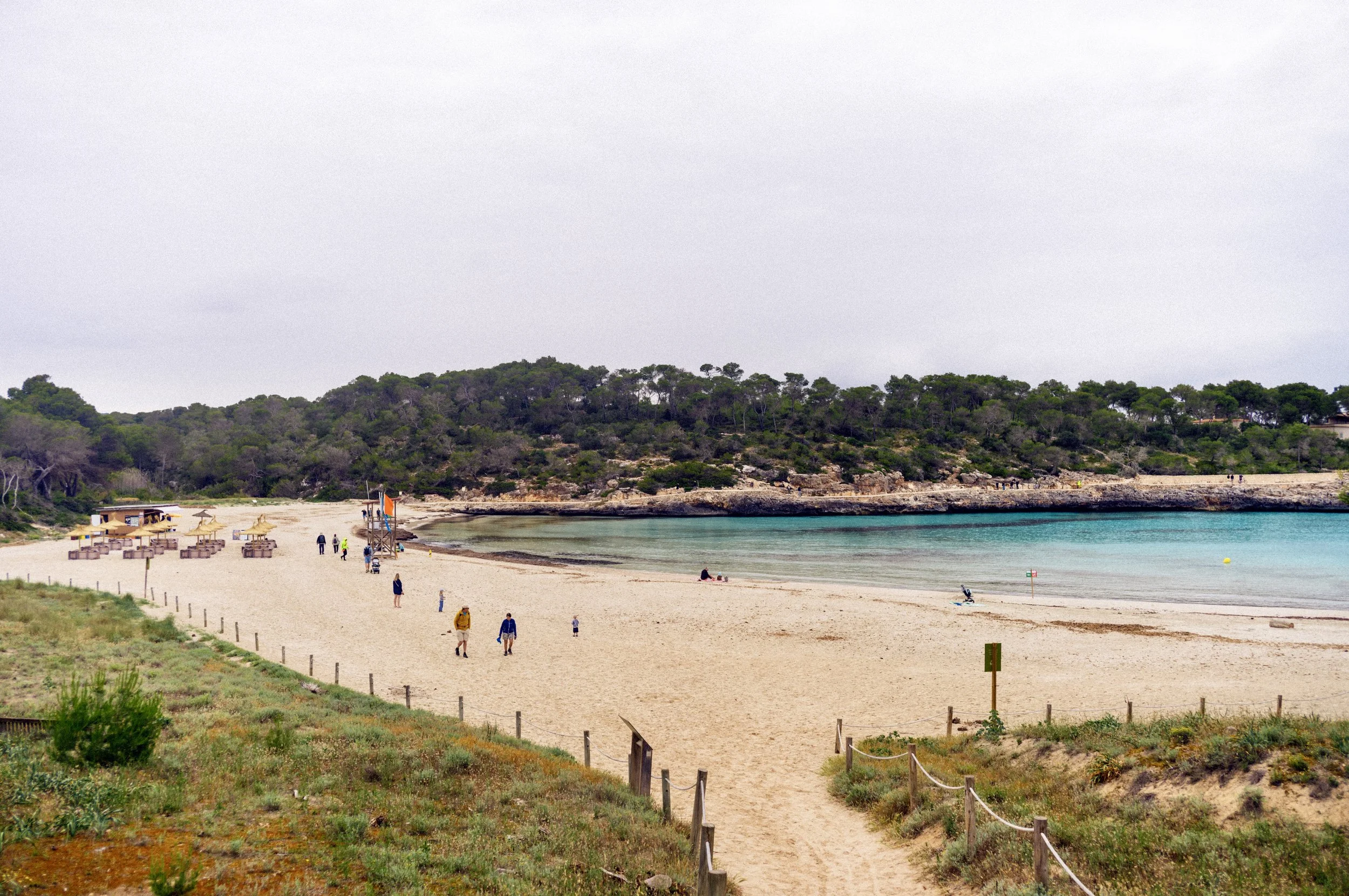Wide sandy beach and turquoise bay on an overcast day at Mondragó Natural Park, Mallorca