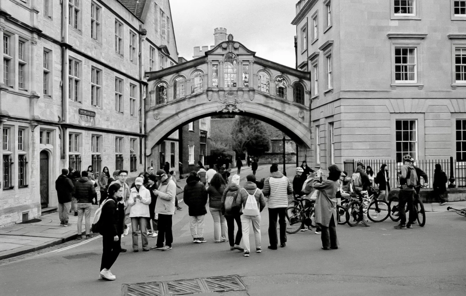 Black and white film photo of the Bridge of Sighs in Oxford with tourists and cyclists on New College Lane