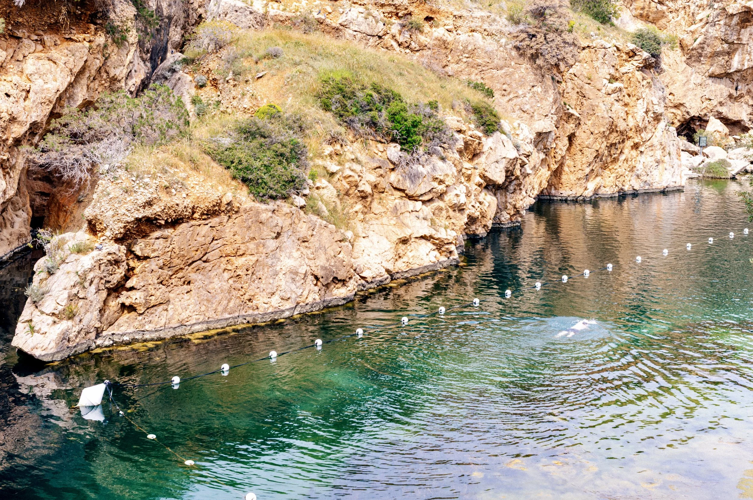 Vouliagmeni Lake coastal thermal spa near Athens Greece with calm water and rocky shoreline