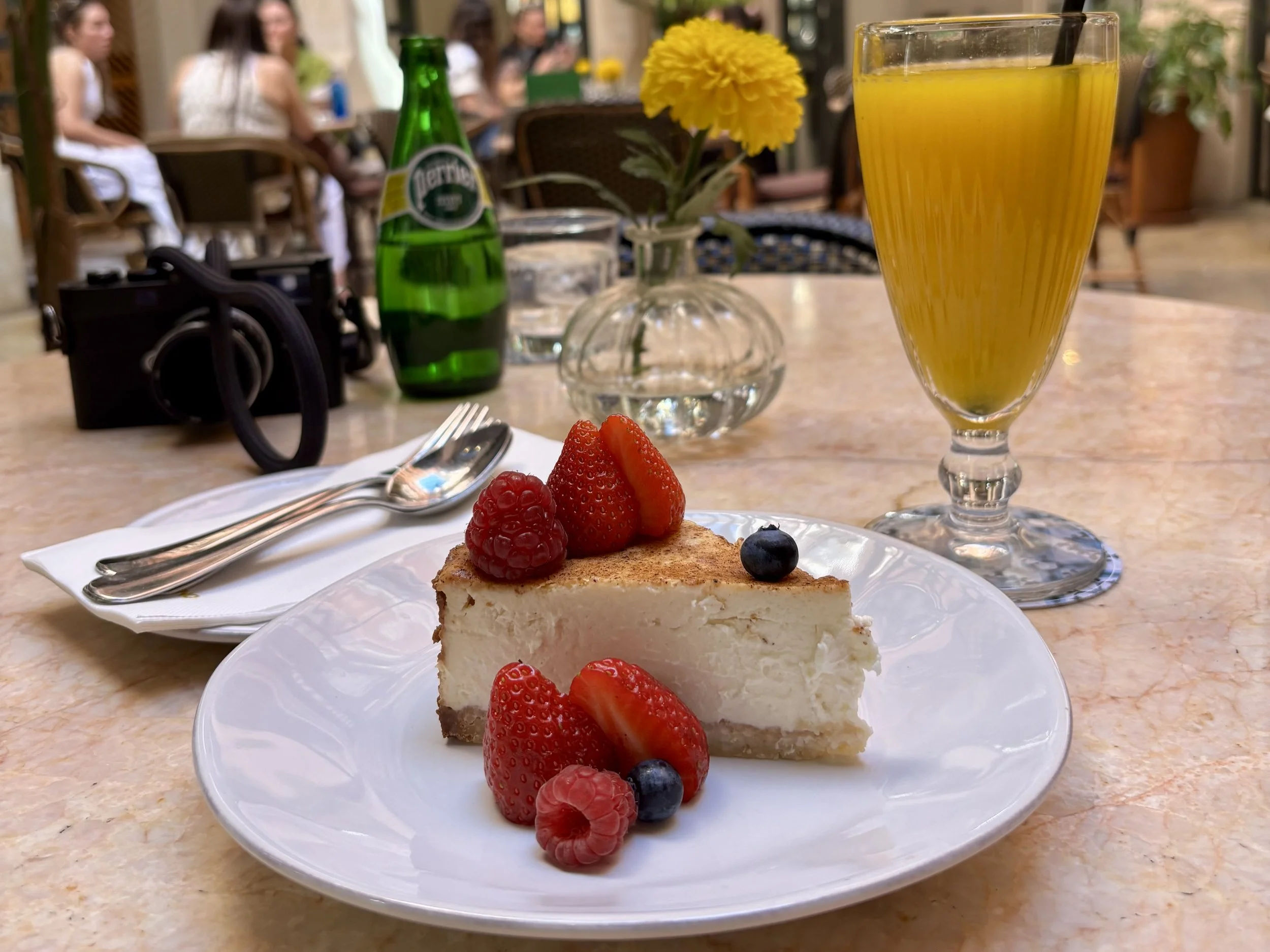 lice of cheesecake topped with berries beside a mimosa at a marble café table in Mallorca