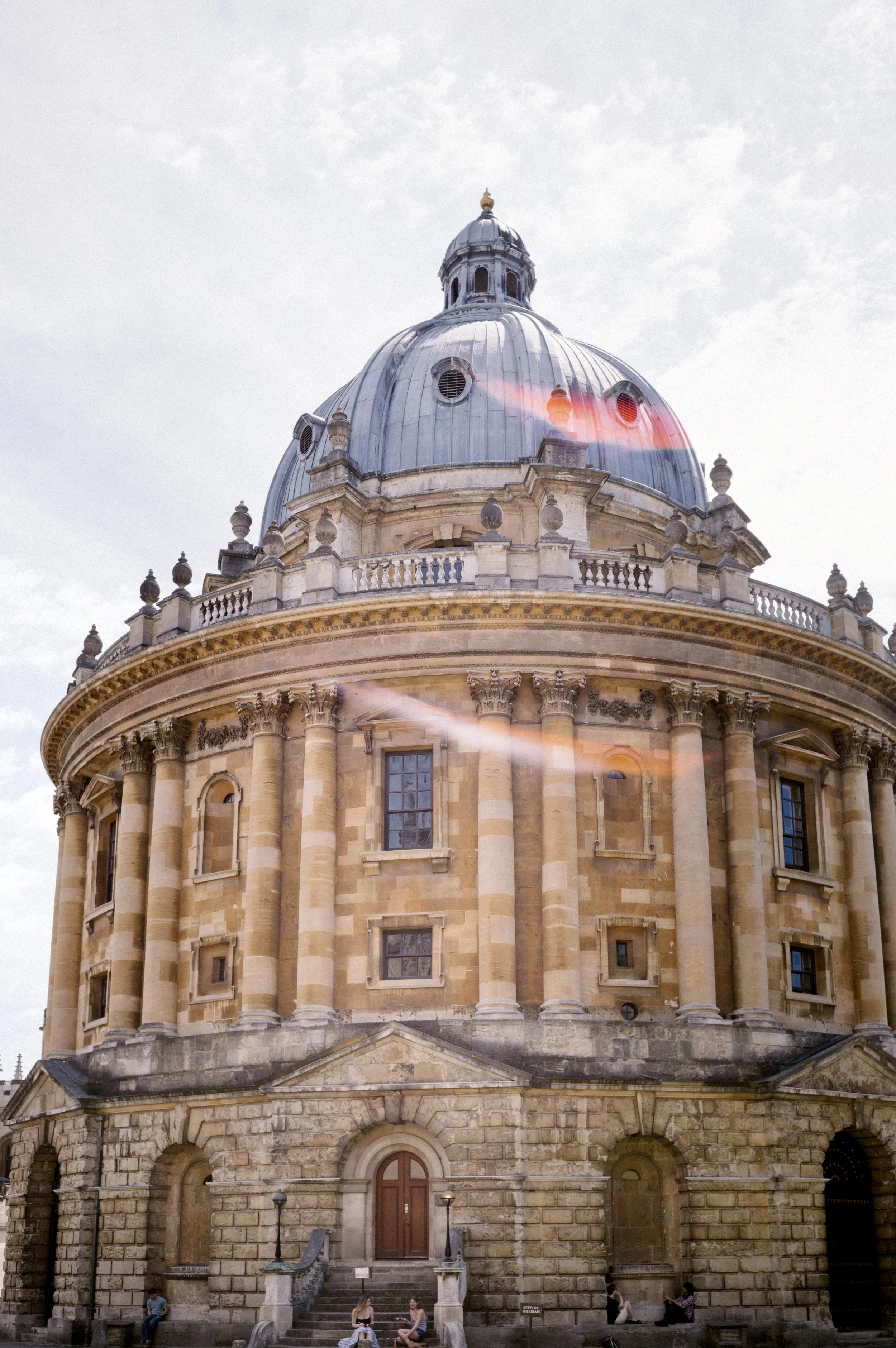 Radcliffe Camera domed library building in Oxford, England, with students sitting on the steps