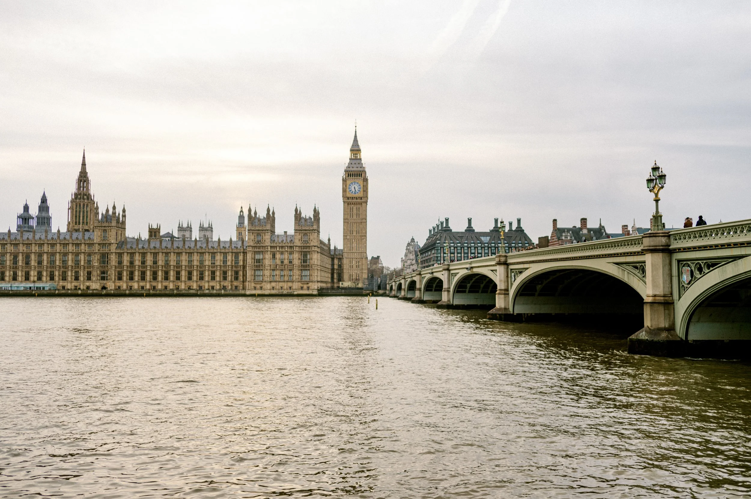 View across the River Thames towards Big Ben, the Palace of Westminster, and Westminster Bridge in London during late afternoon light.