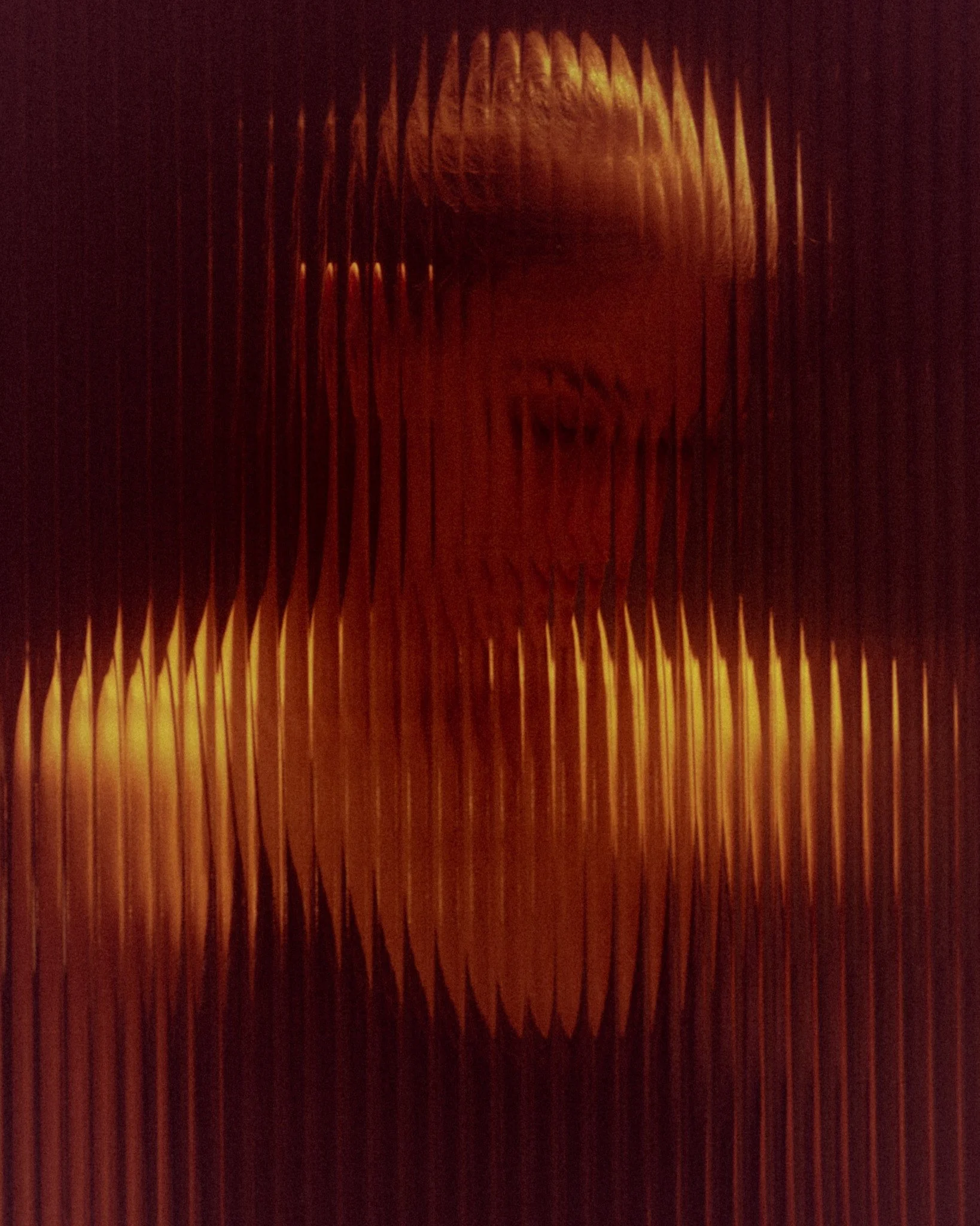 Close-up of a textured, amber-colored, ribbed glass surface with a light source behind it.