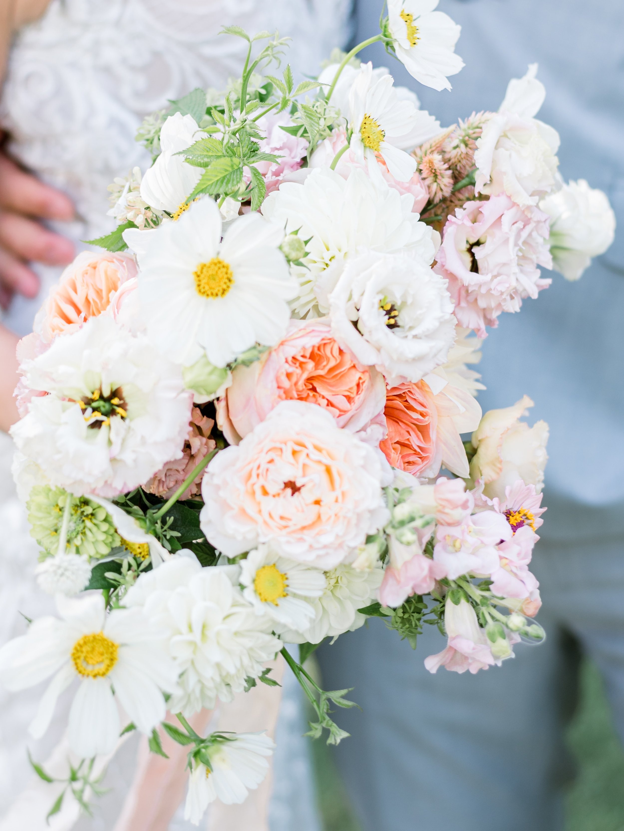 Close-up of a colorful bouquet of white, pink, and peach flowers, including daisies, roses, and other blooms.
