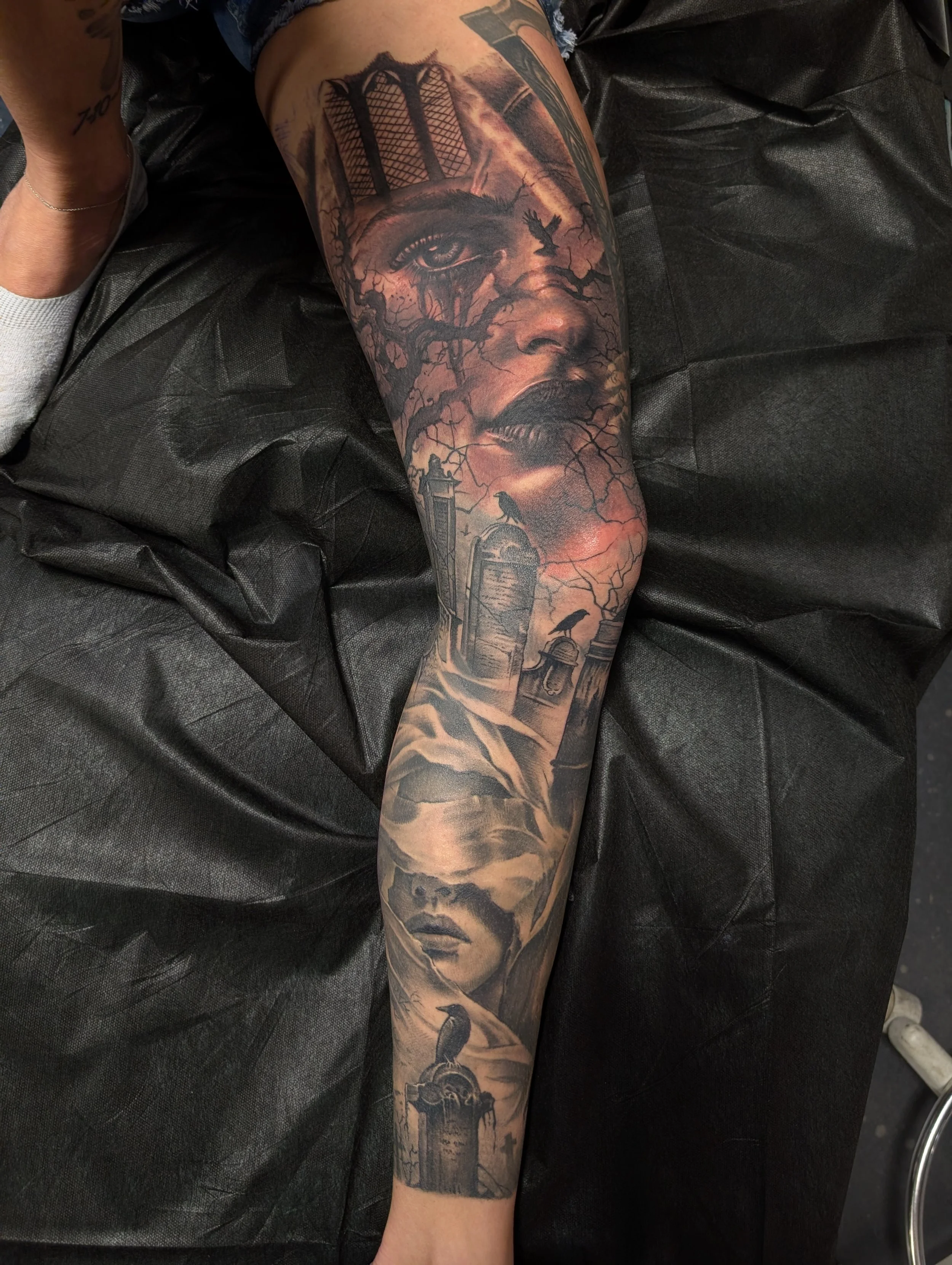 black and grey realism inner leg sleeve with female faces and gravestones