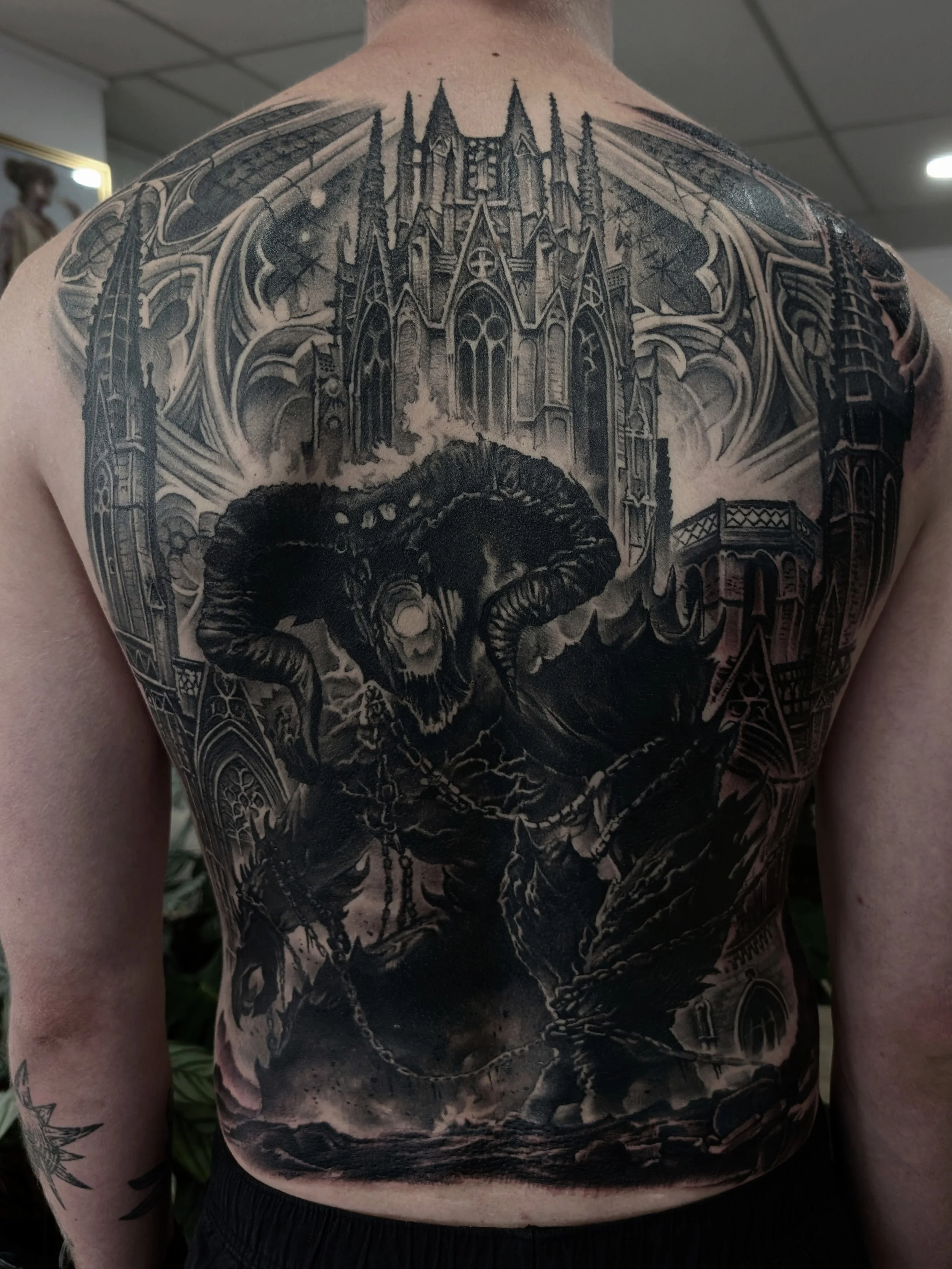 Full black and grey backpiece of a Balrog demon in front of a gothic cathedral