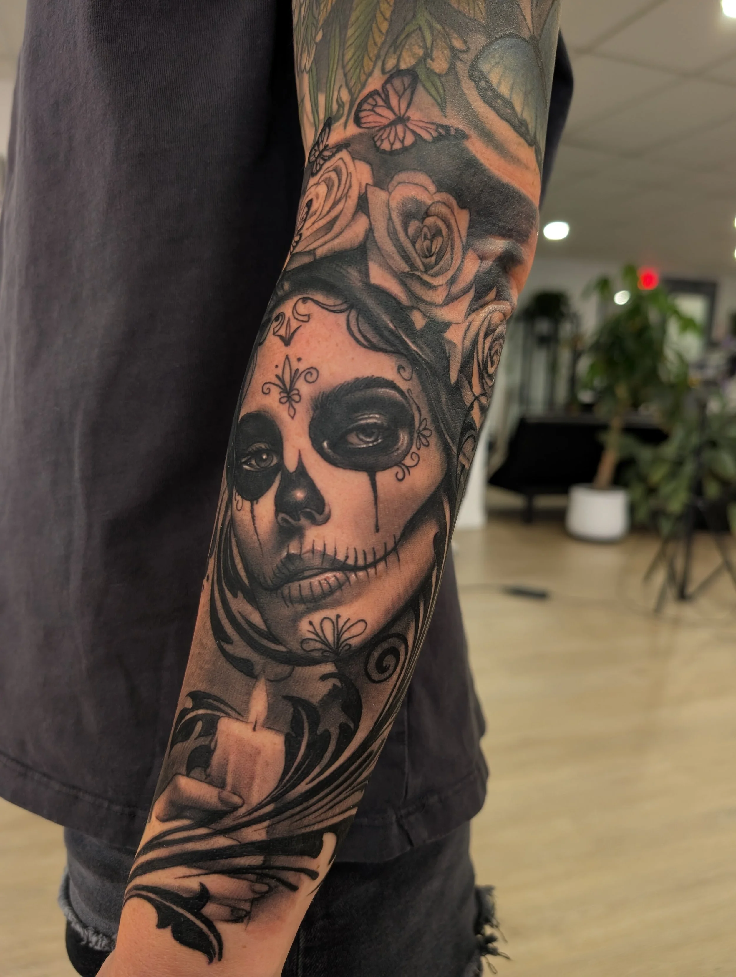 black and grey realism forearm tattoo with a day of the dead female portrait and a candle