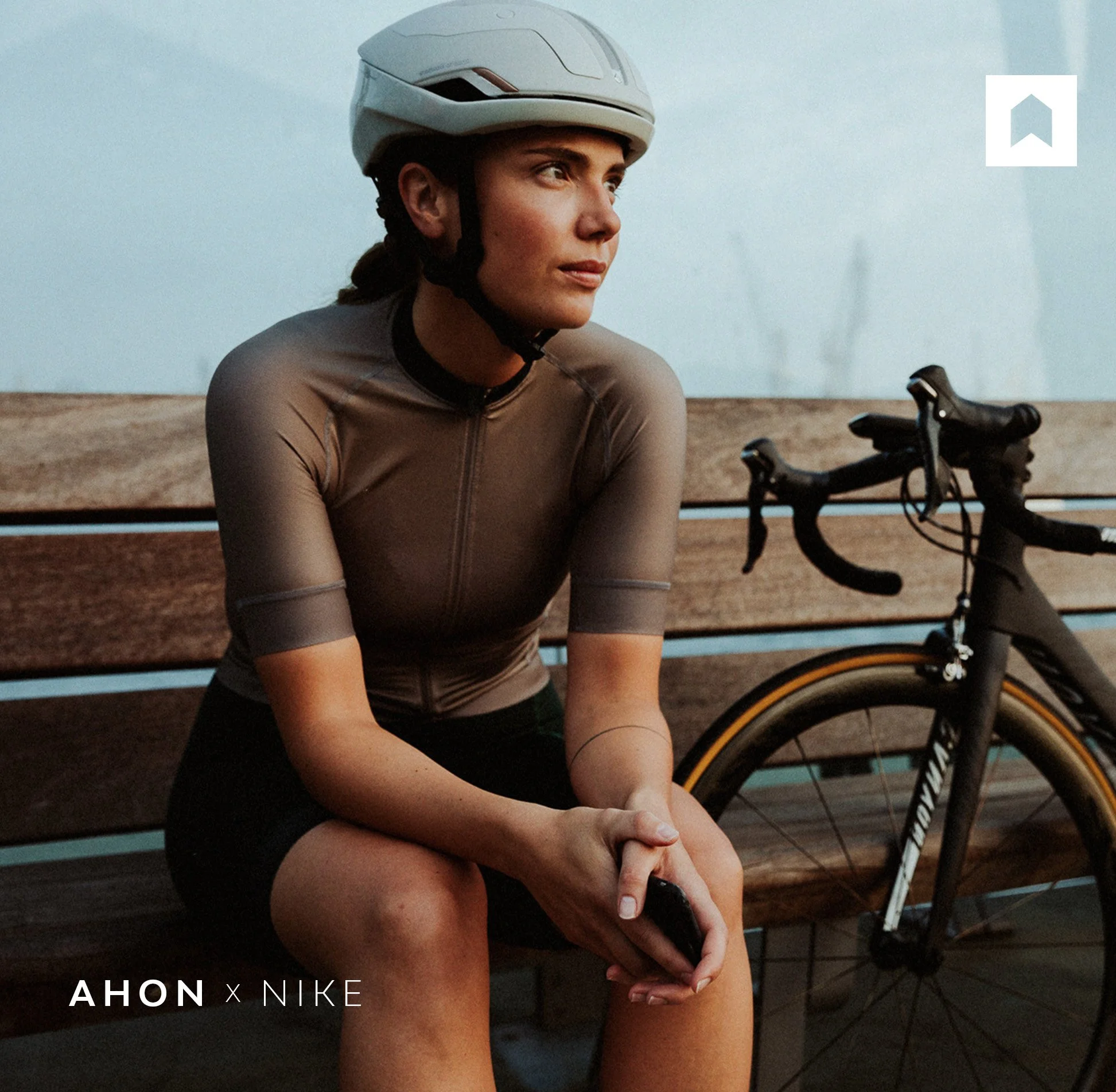 Ahon Technically Subtle brand concept featuring a cyclist seated beside a bicycle with minimal logo placement.