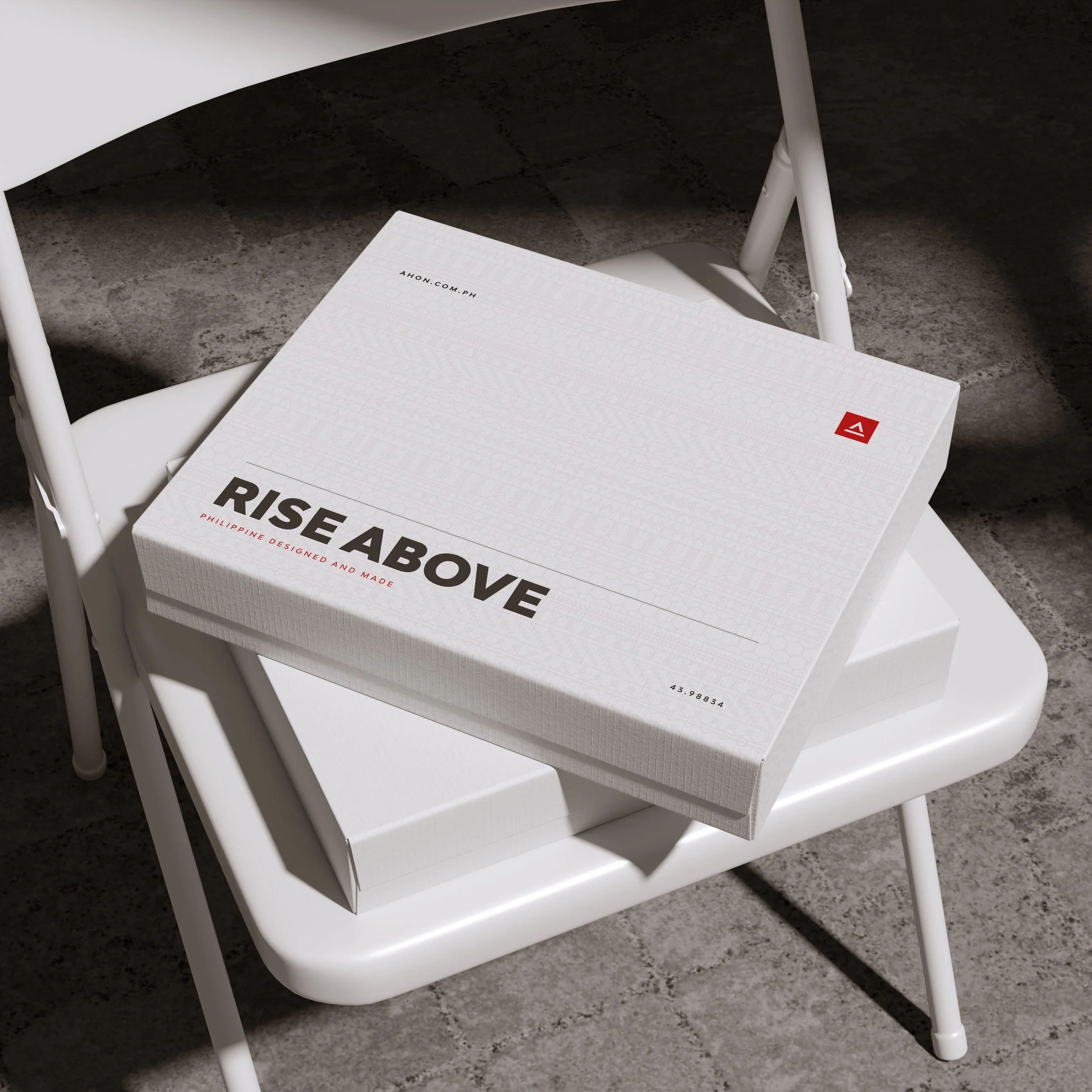 White Ahon packaging boxes with Rise Above lettering and a small red brand mark, stacked on a chair.