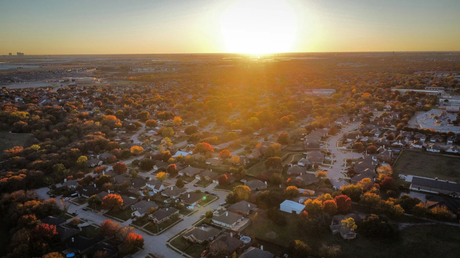 Aerial view of a suburban neighborhood with fall trees at sunset