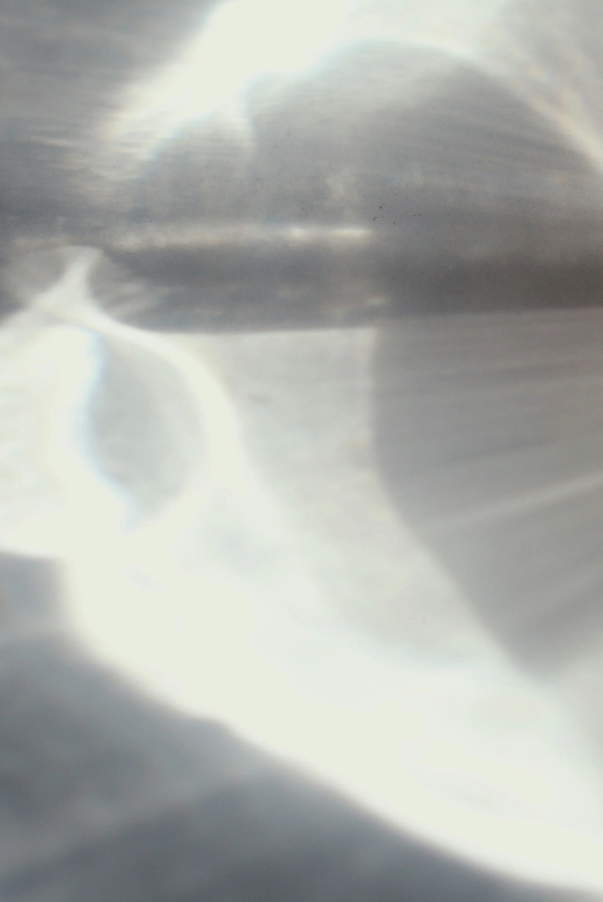 Close-up of a metallic object with light reflections and shadows, possibly a shiny tool or piece of hardware.