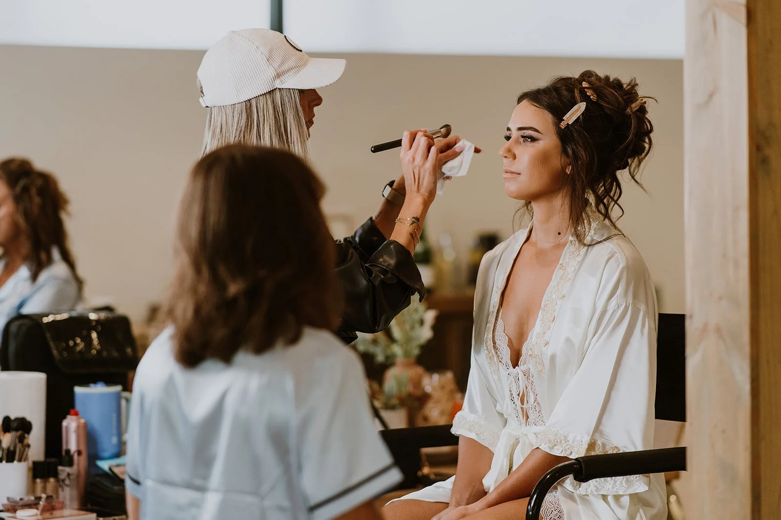 Megan Evans doing makeup on a bride sitting in a white robe
