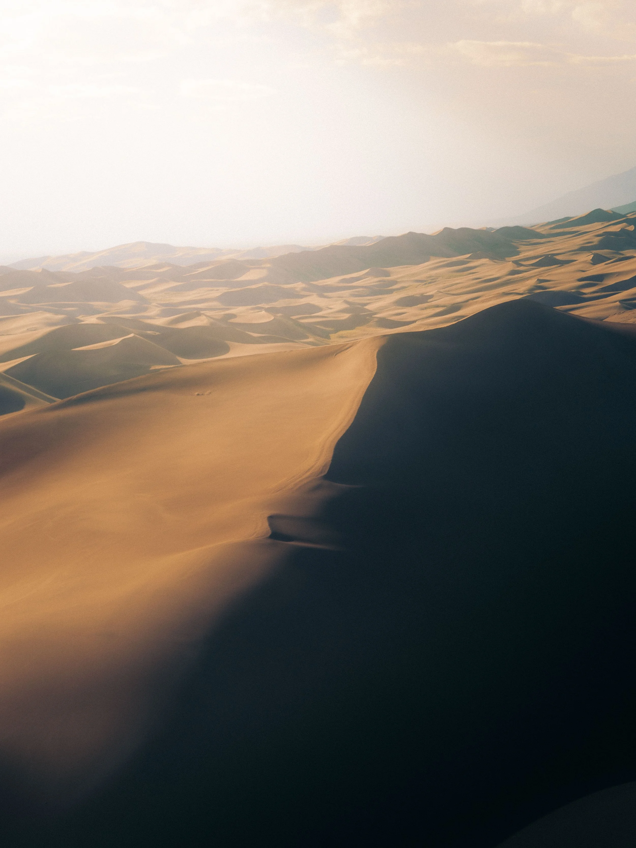 A vast desert landscape with golden sand dunes and clear sky.