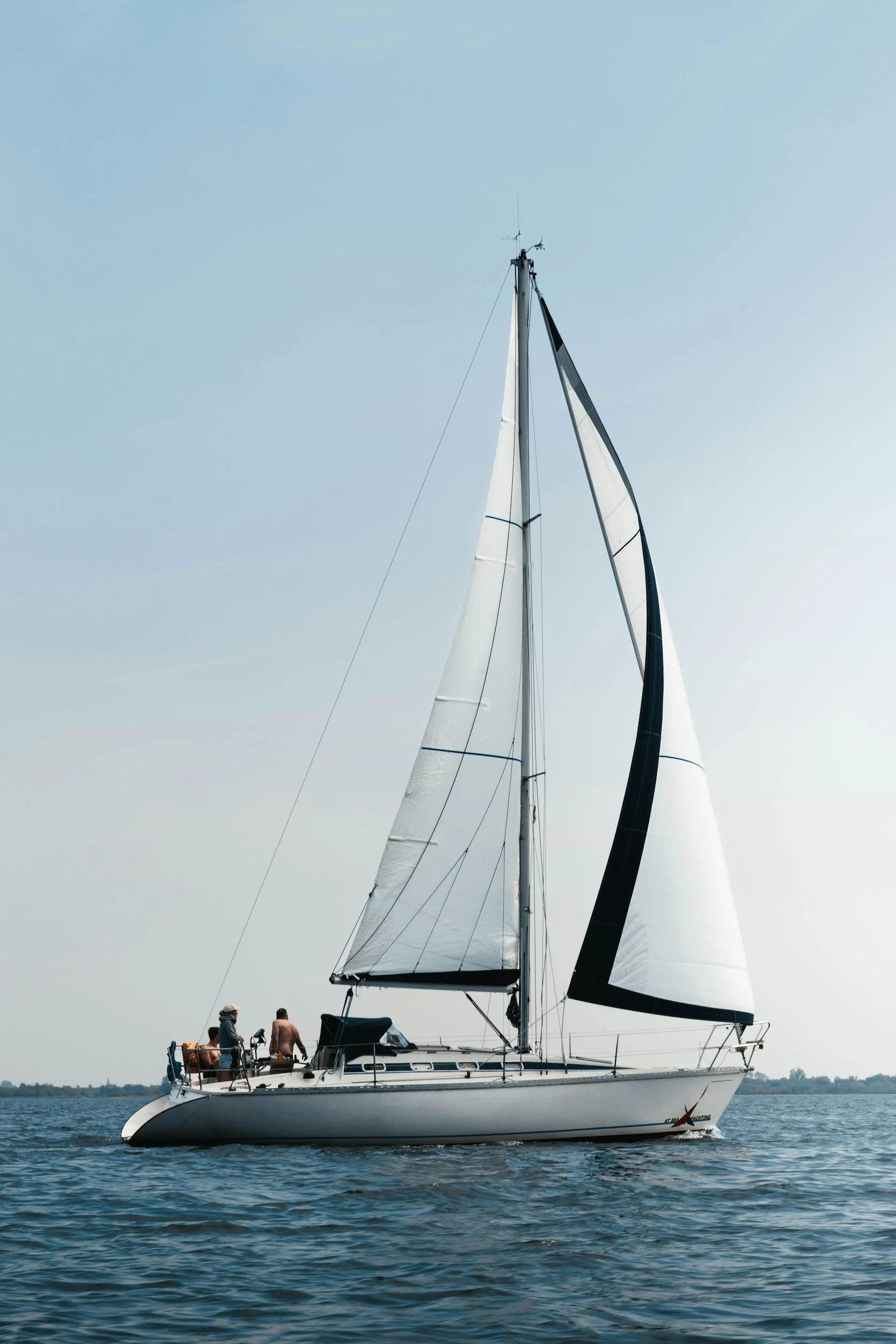 Sailboat with people in open water on a clear day