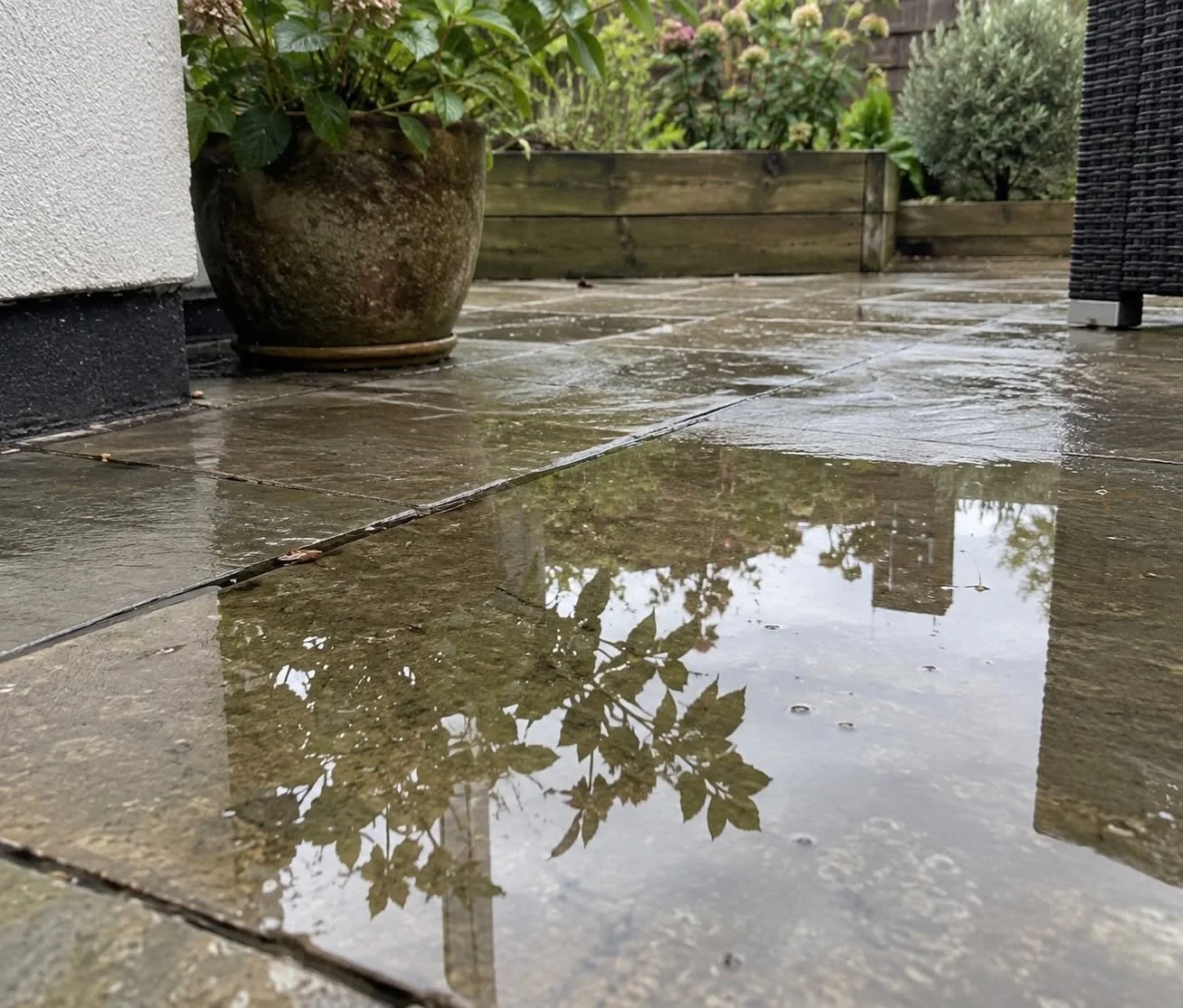 Rainwater collecting on a paved garden patio after heavy rain in Cornwall