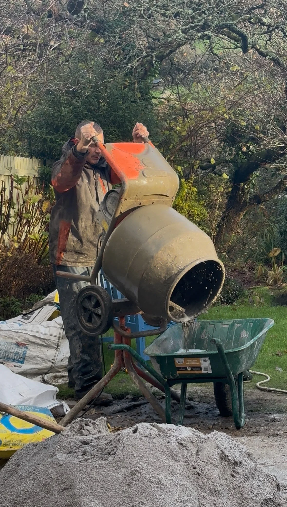 Tom from Rashleigh & Son with a cement mixer in Cornish garden installing a patio.