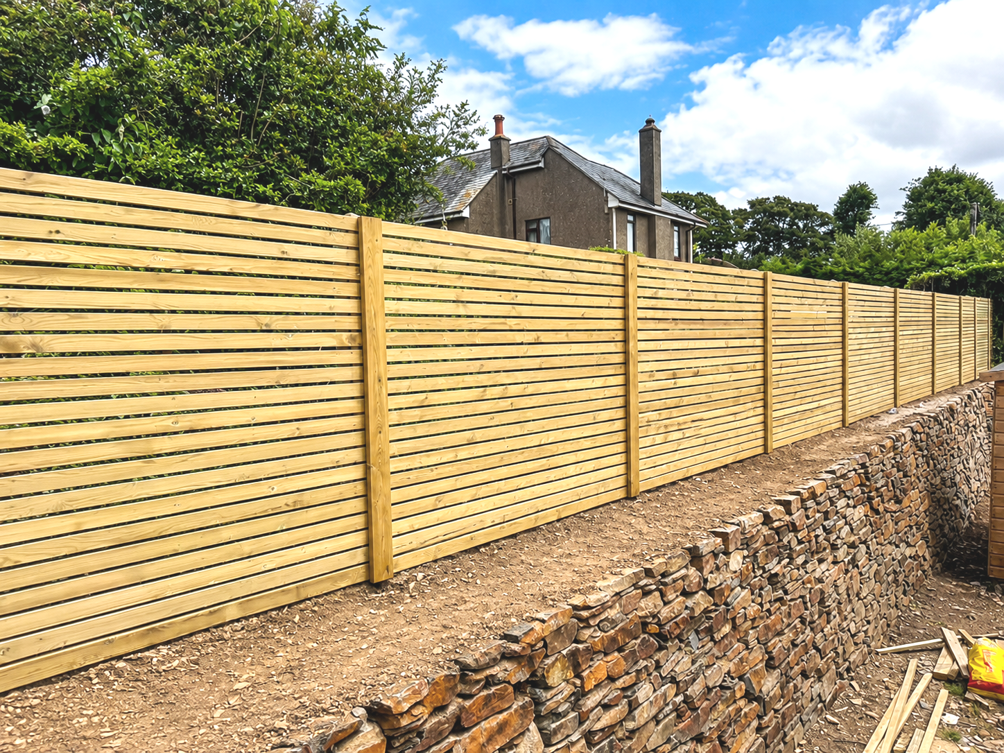 New timber garden fencing above a traditional Cornish stone wall