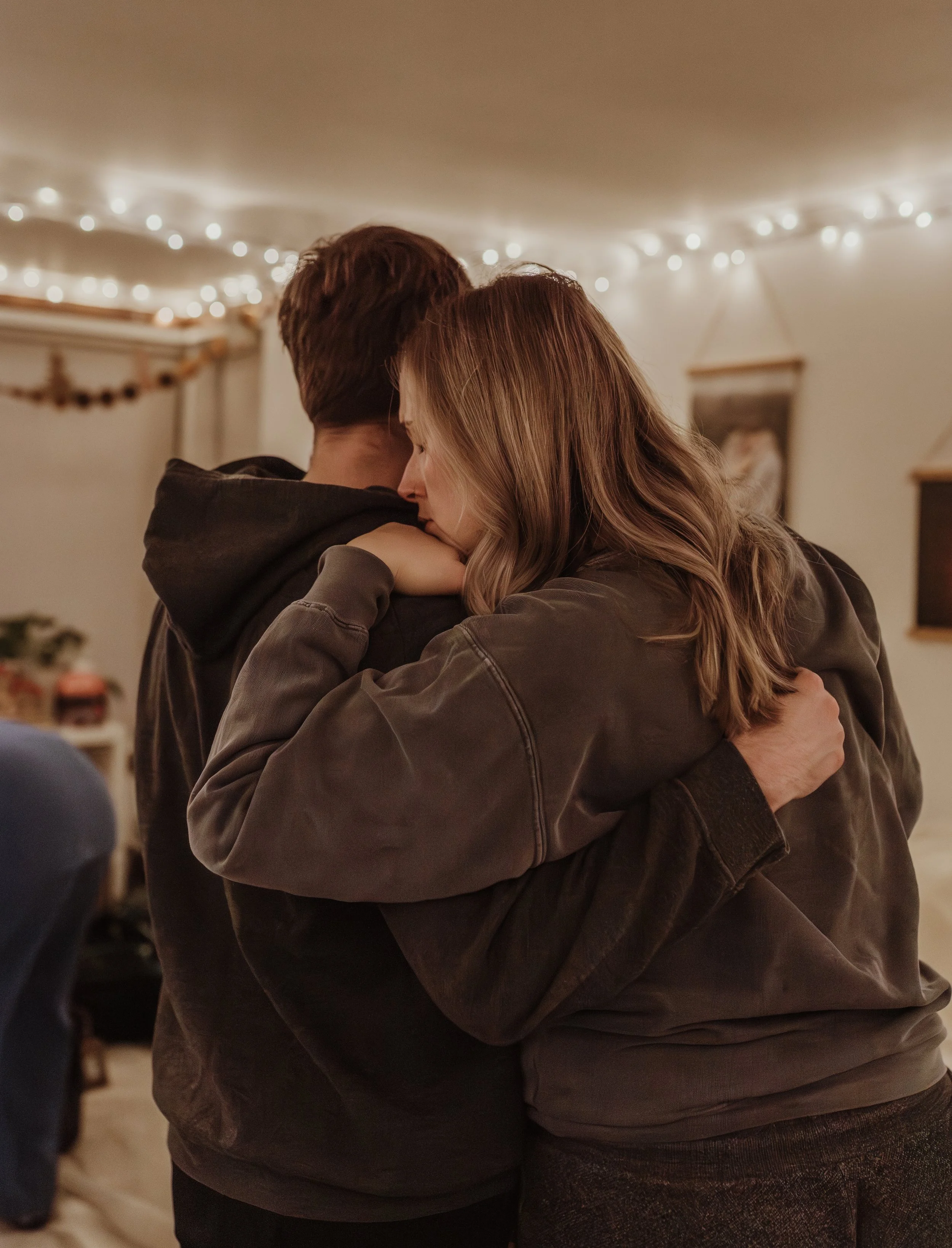 Rebekah and James holding each other close during early labour at their Glasgow home birth, surrounded by fairy lights and a homemade Christmas garland
