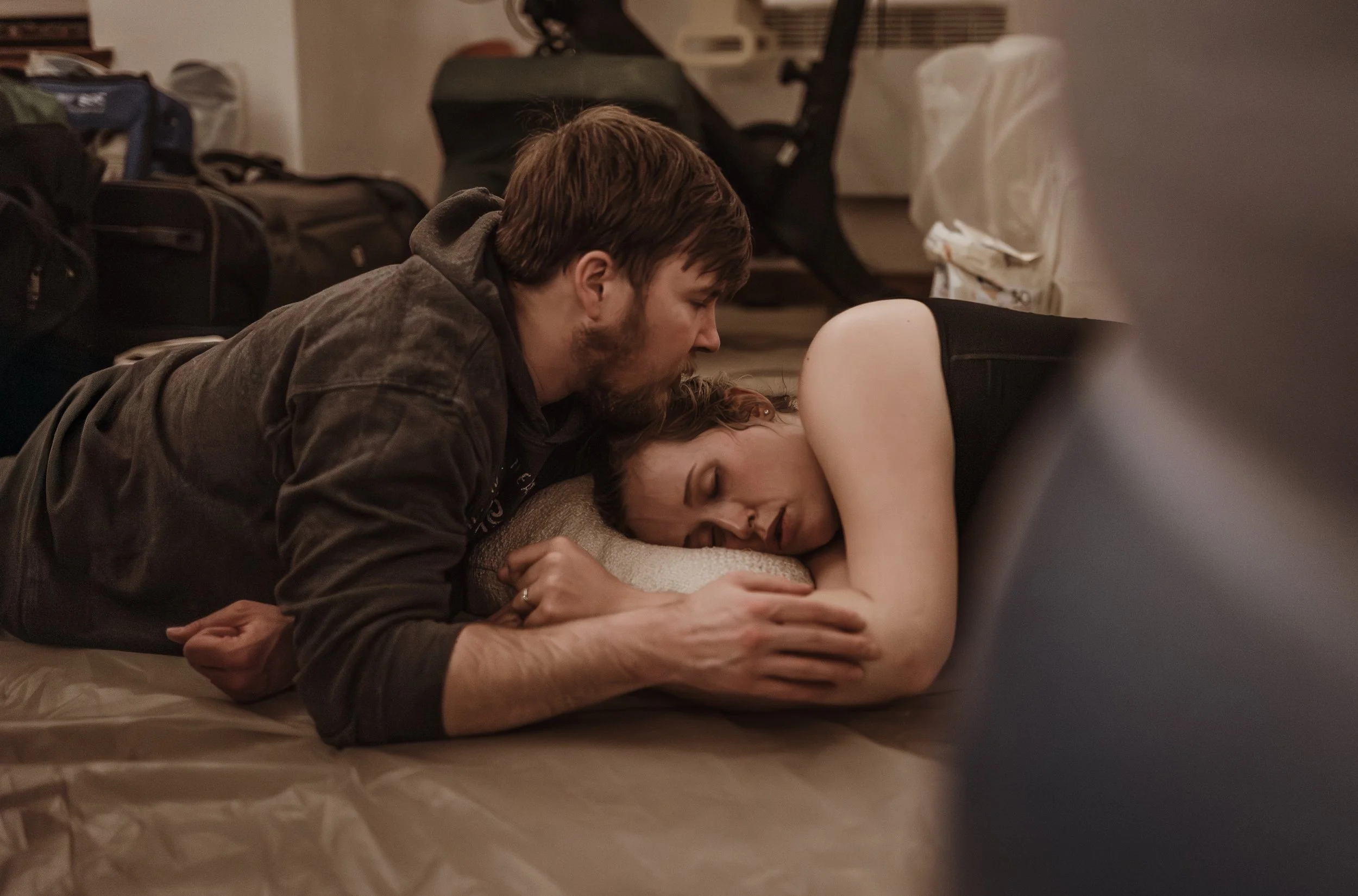 James lying beside Rebekah on the floor between contractions during active labour at their Glasgow home birth, the quiet strength he offered described in her own words