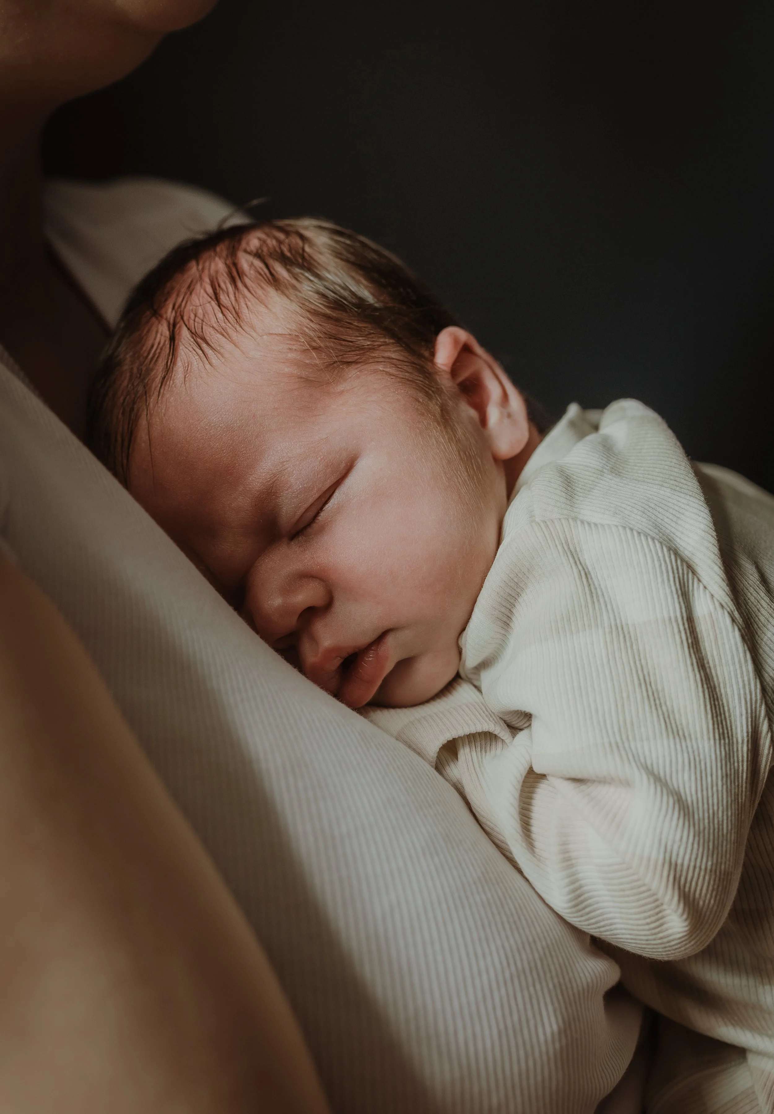 Newborn baby sleeping peacefully on a parent's chest during an at-home newborn photography session in Glasgow with Marieke Captures Birth
