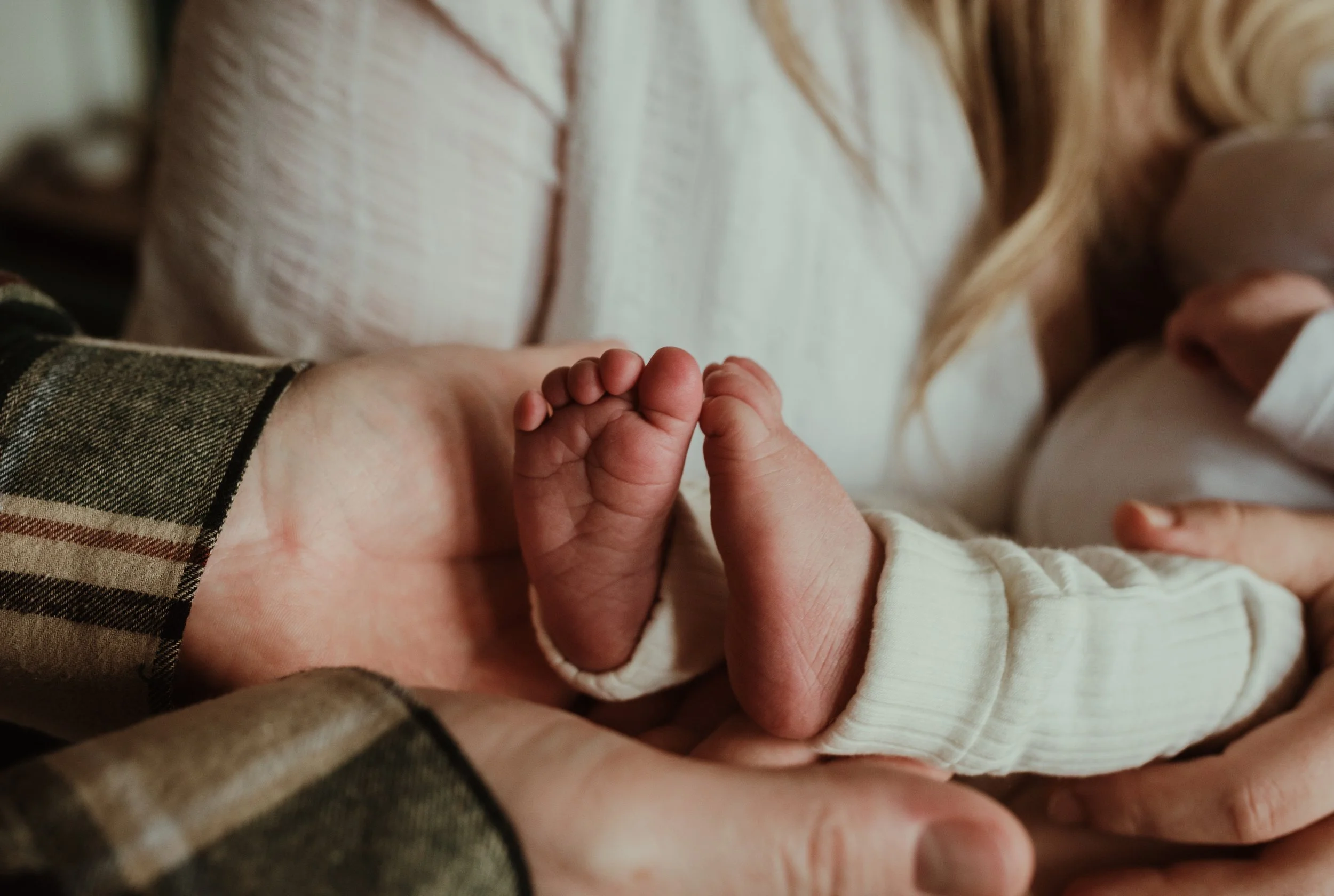 Close up of parent hands gently holding newborn baby's feet during an at-home newborn photography session in Scotland with Marieke Captures Birth