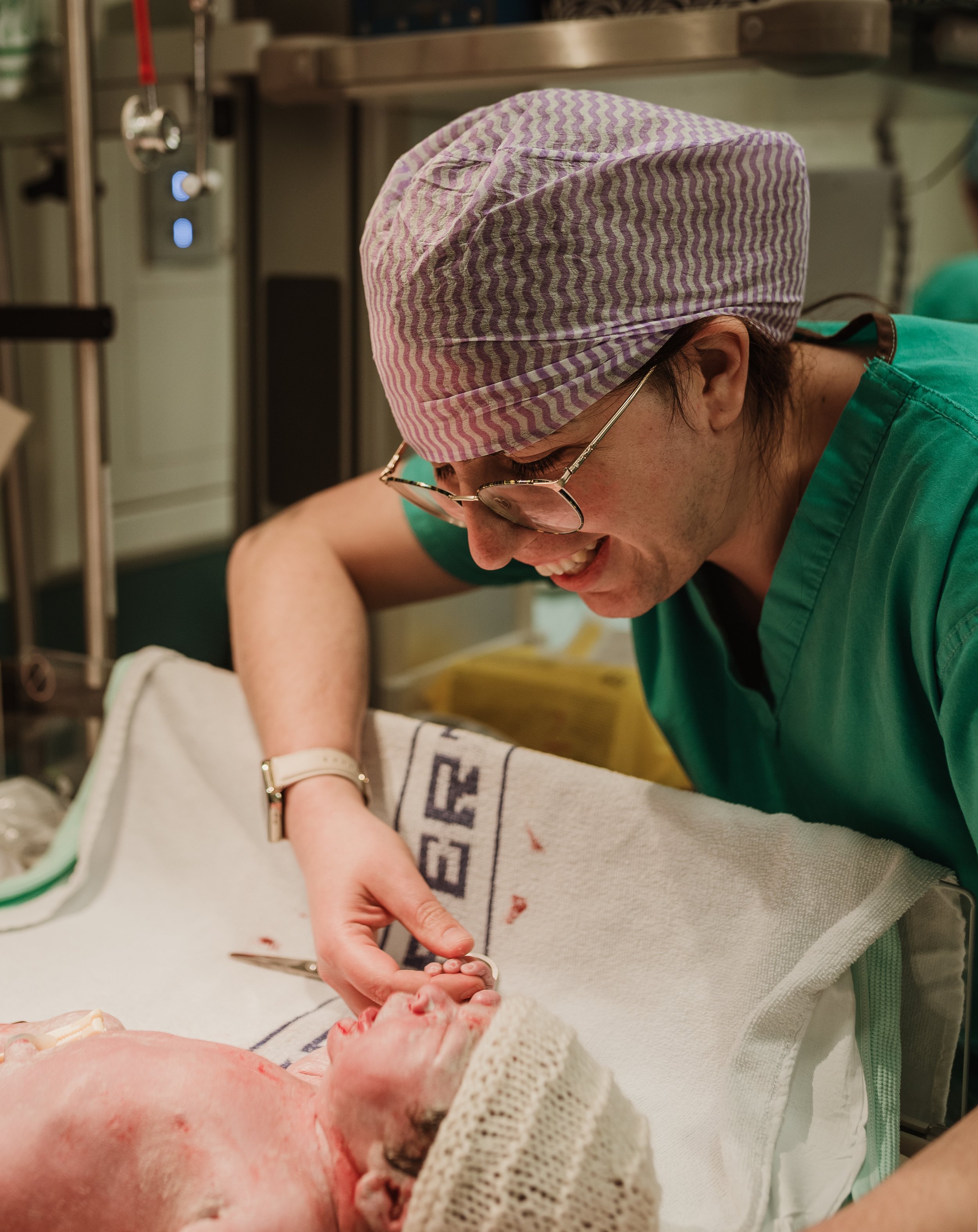 Partner in surgical cap attending to newborn in theatre, Glasgow — birth photography by Marieke Captures Birth
