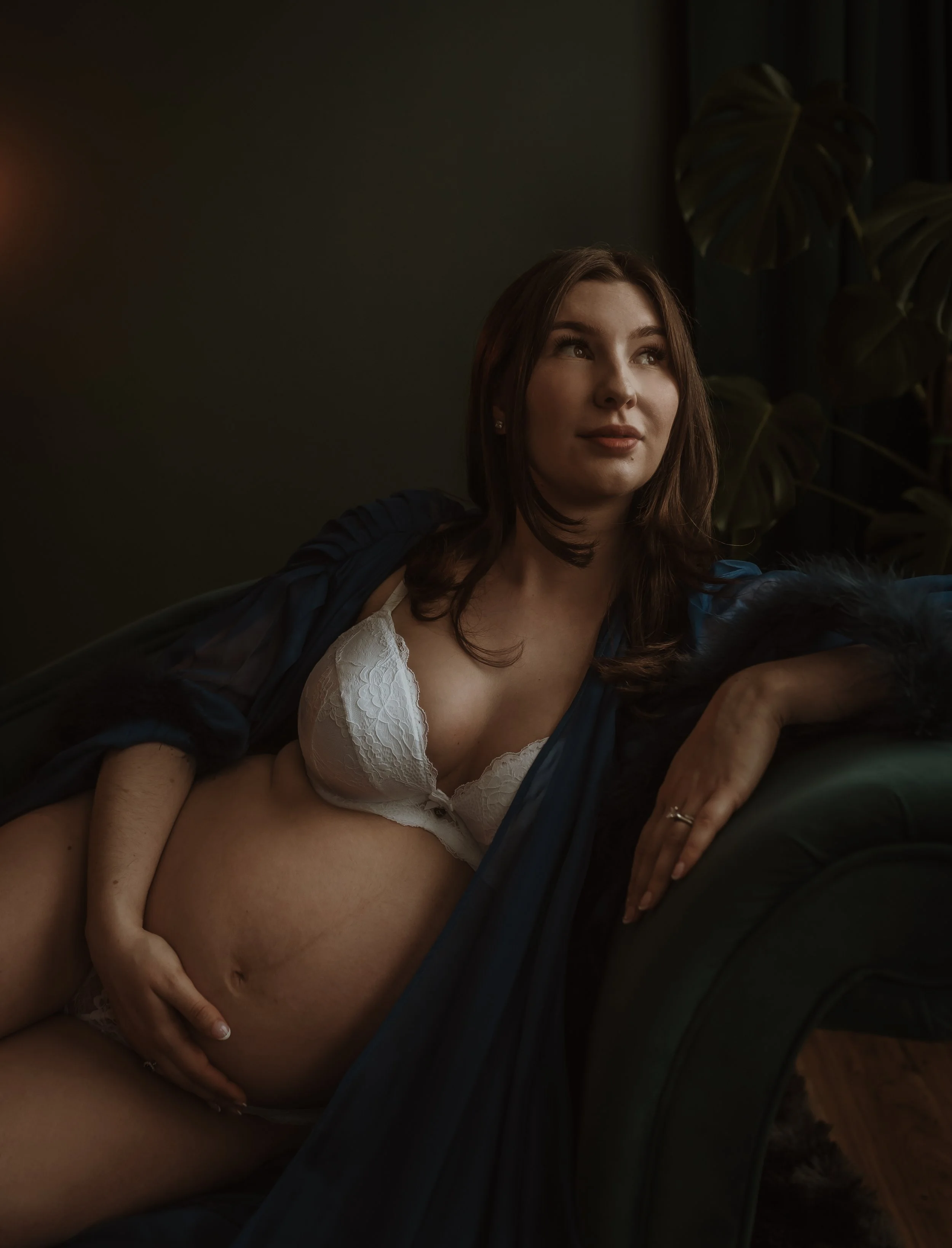 Pregnant woman seated on a velvet chair in white lingerie and blue drape during a studio maternity session in Glasgow with Marieke Captures Birth