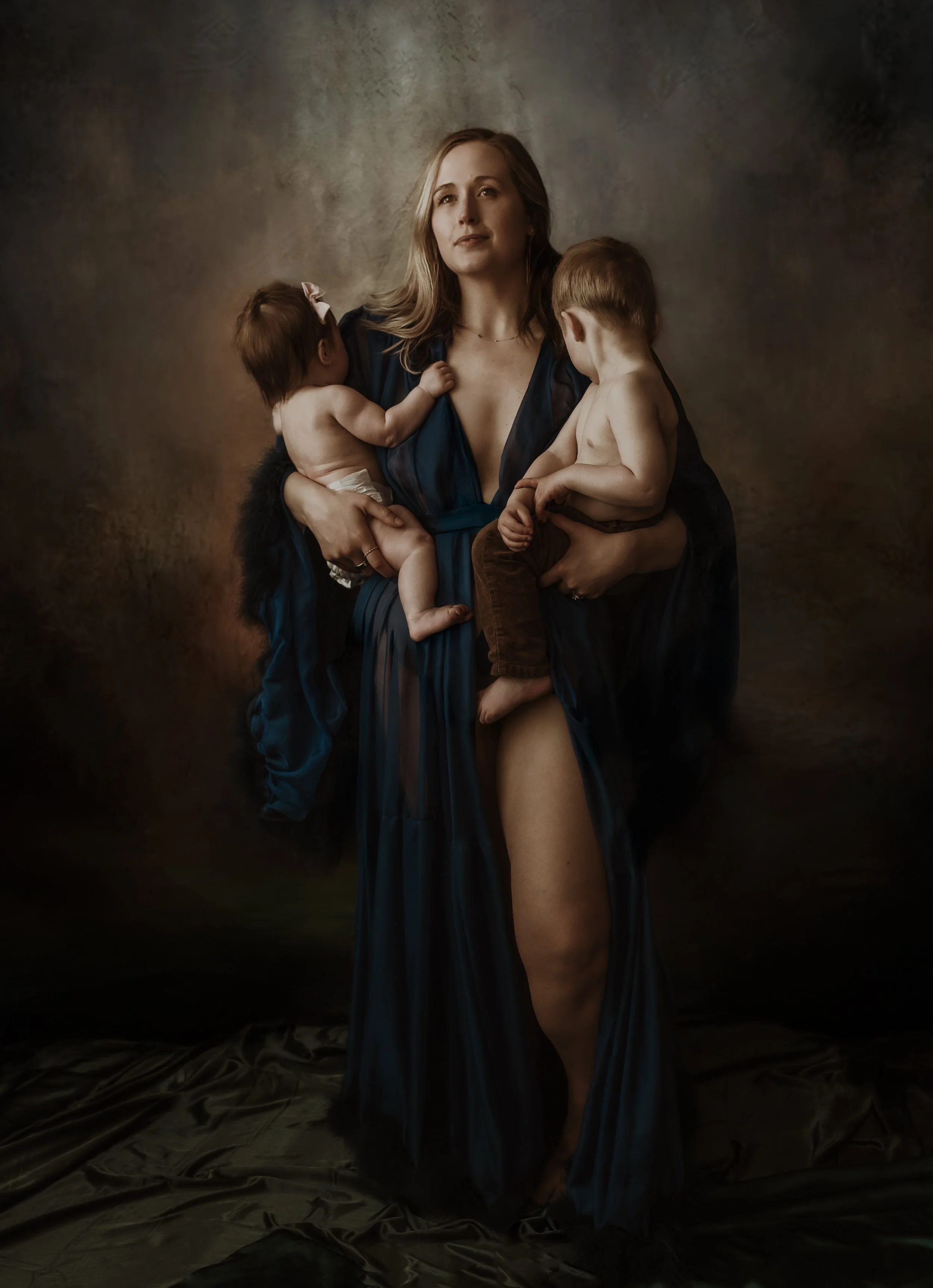 Studio portrait of a mother in a dark blue dress holding her baby during a nursing photography session with Glasgow photographer Marieke Captures Birth
