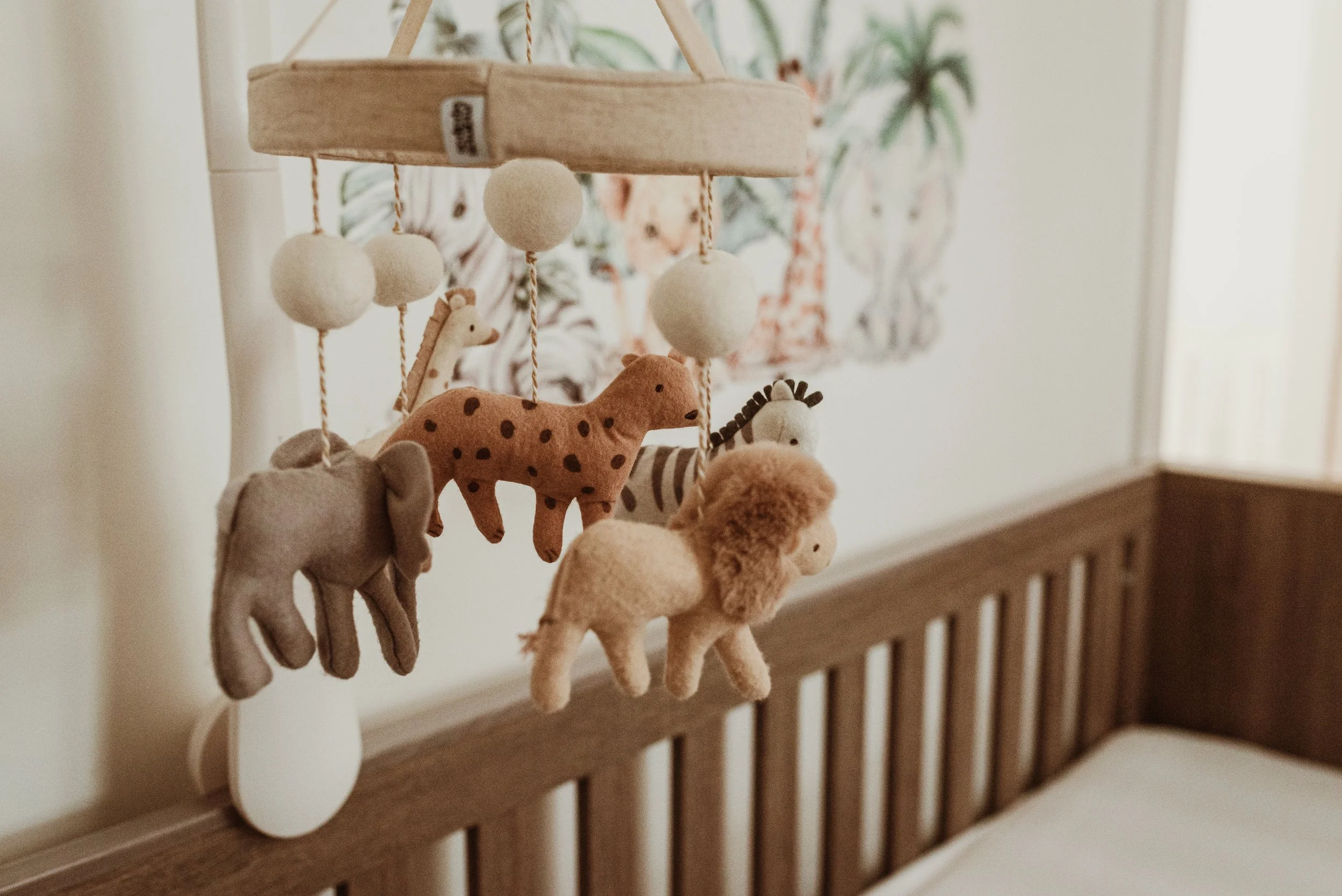  Wooden animal cot mobile above a white cot in a nursery, documented during an at-home newborn photography session in Glasgow with Marieke Captures Birth