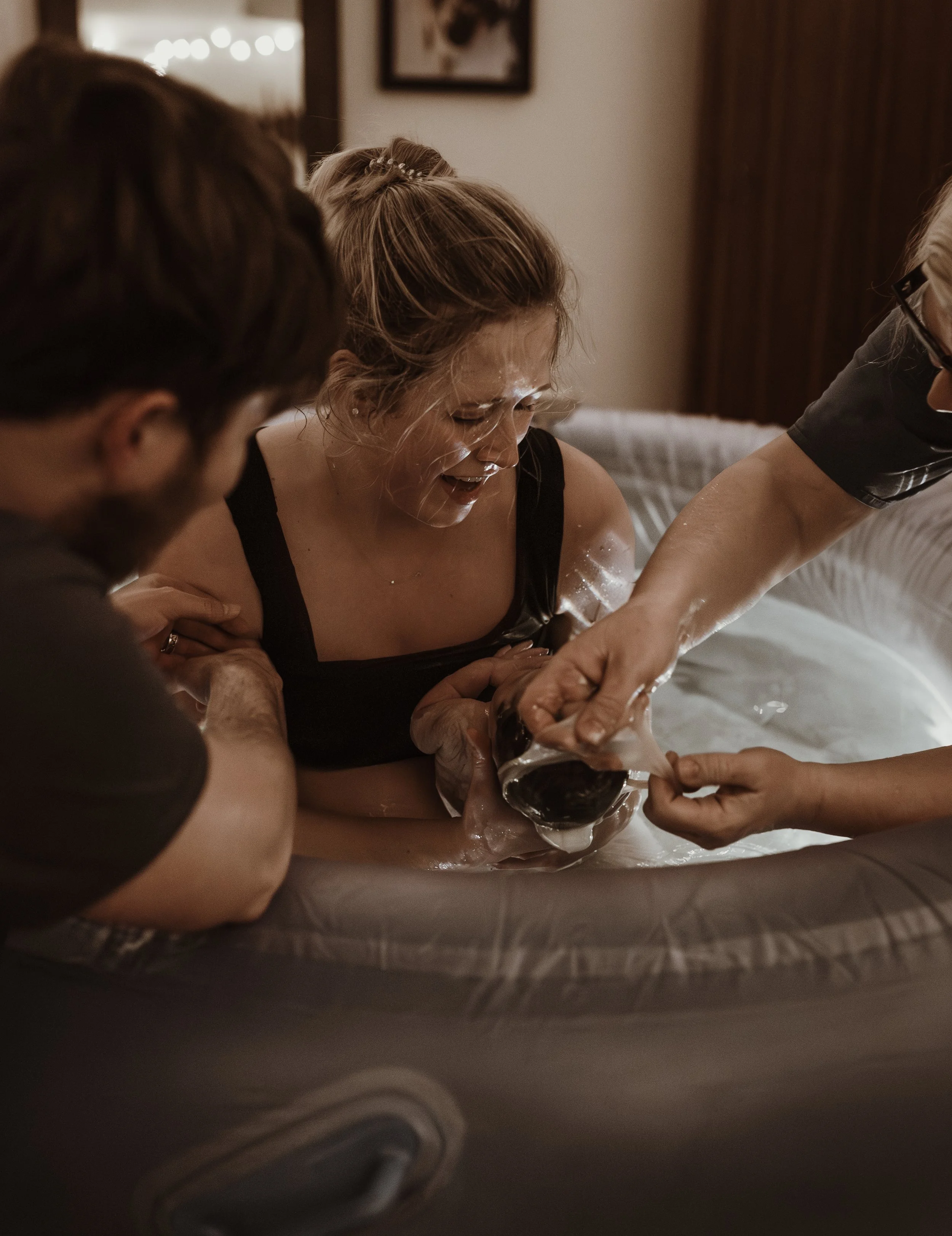 Rebekah holding her newborn daughter for the first time after a Glasgow home water birth, looking at James with pure joy