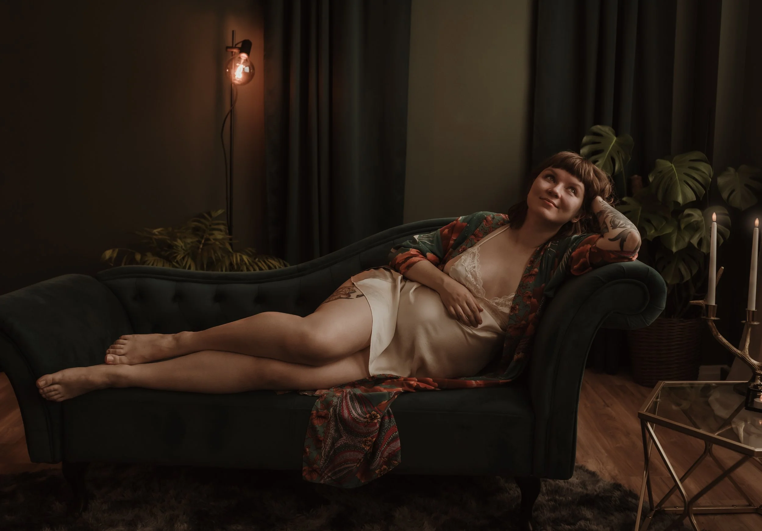 Pregnant woman lying relaxed on a velvet sofa surrounded by warm candlelight during a studio maternity session with Glasgow maternity photographer Marieke Captures Birth