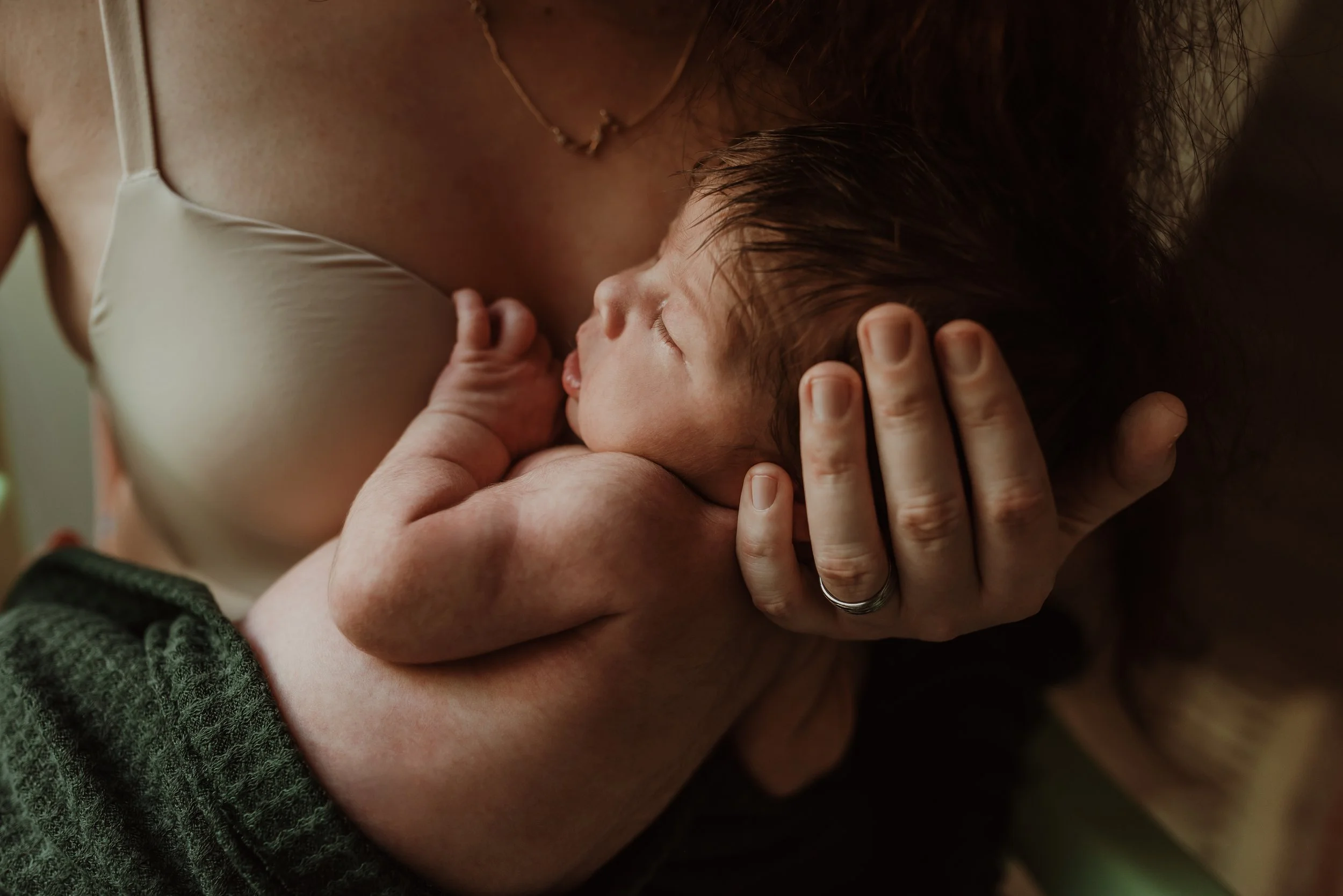 Mother holding her newborn close with both hands visible during an at-home newborn photography session with Glasgow photographer Marieke Captures Birth