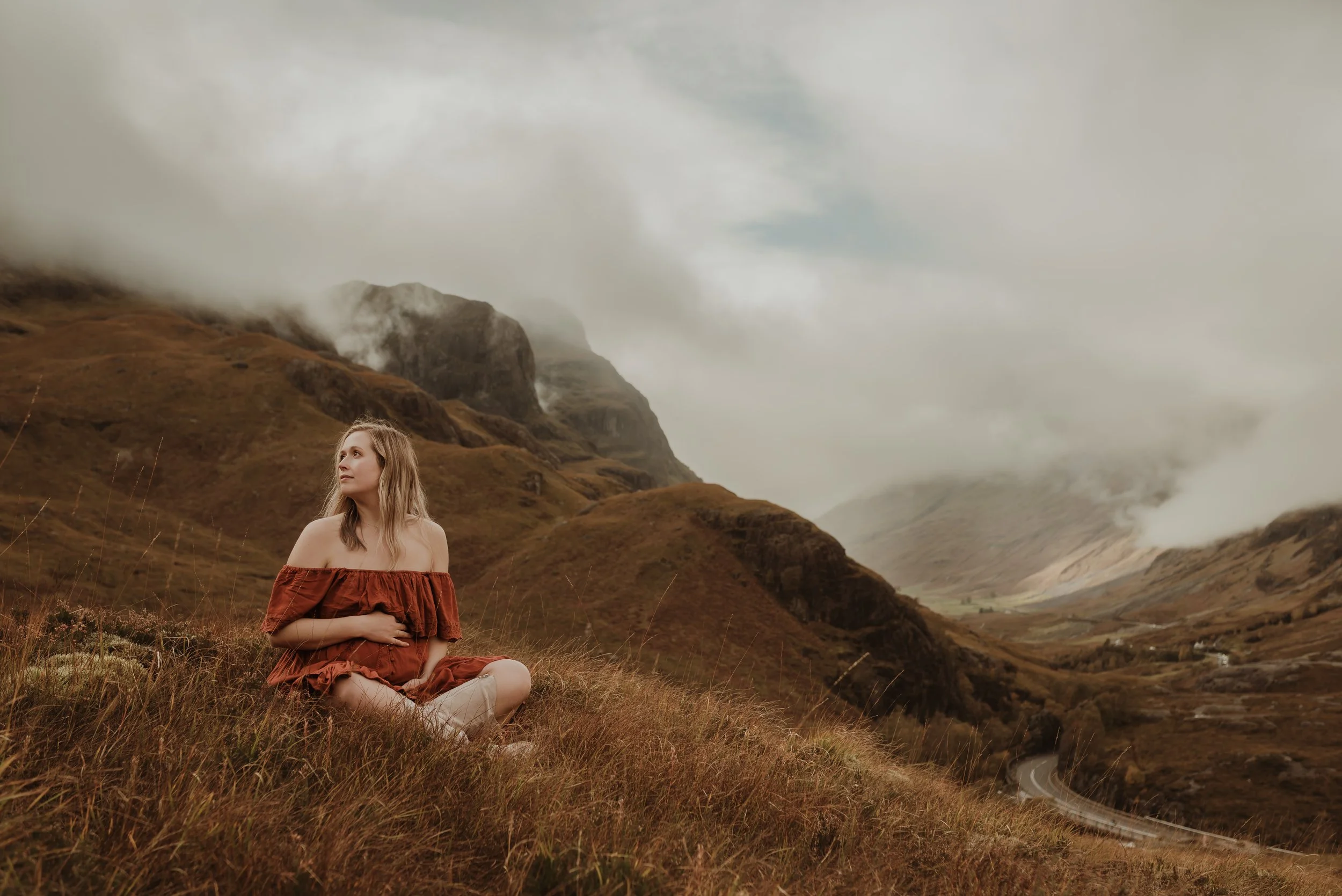 Pregnant mother walking through Glencoe Highland landscape during maternity session