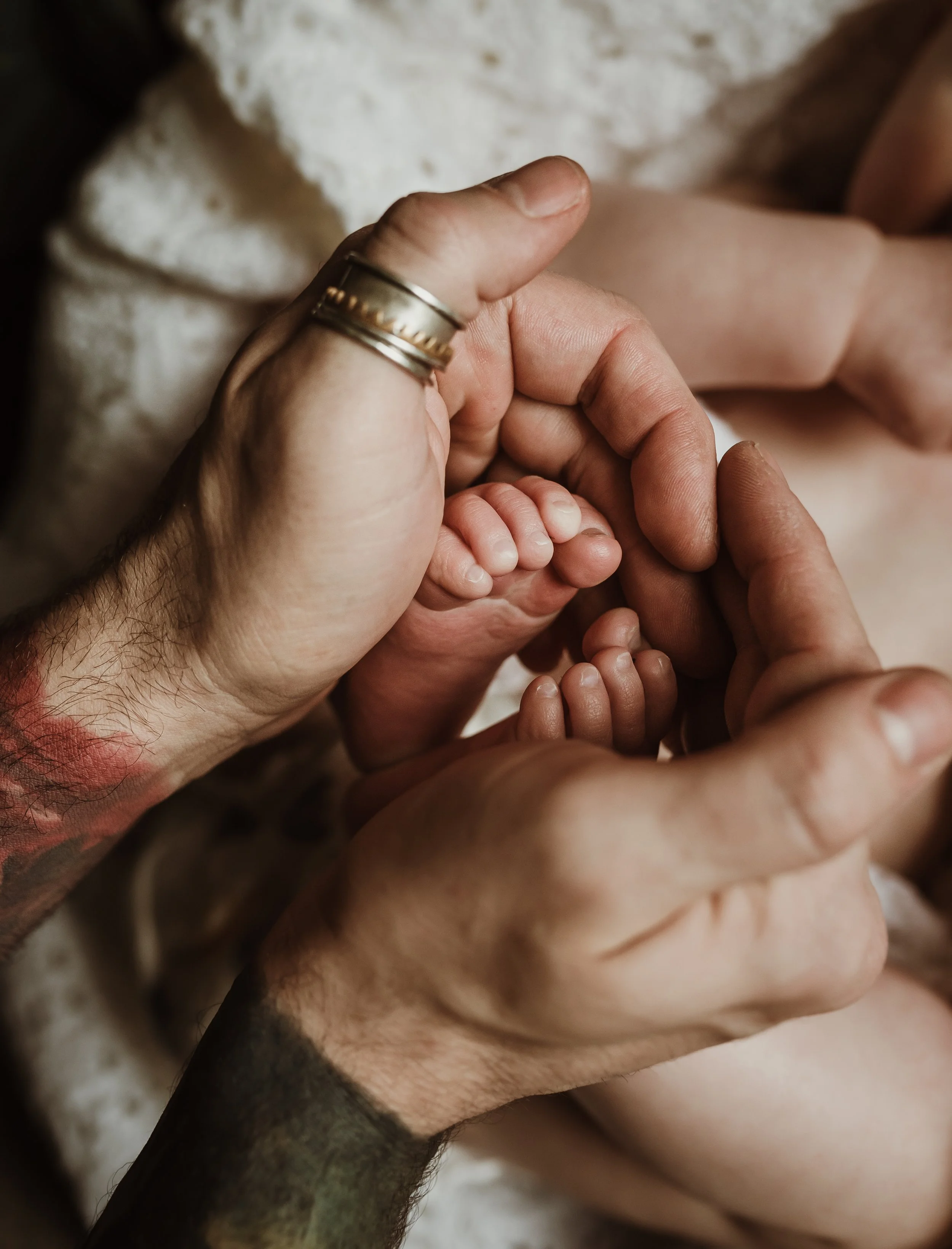 Tiny newborn feet cradled in a parent's hands during a newborn photography session with Glasgow photographer Marieke Captures Birth