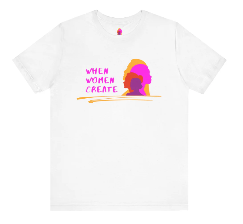 White t-shirt featuring colorful silhouettes of women in shades of pink, purple, and orange, with the text 'When Women Create' in pink on the front.