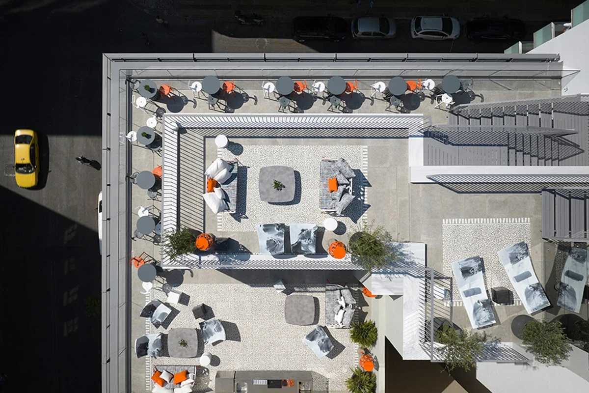 Aerial view of a rooftop terrace with outdoor furniture, seating areas, and orange accents.