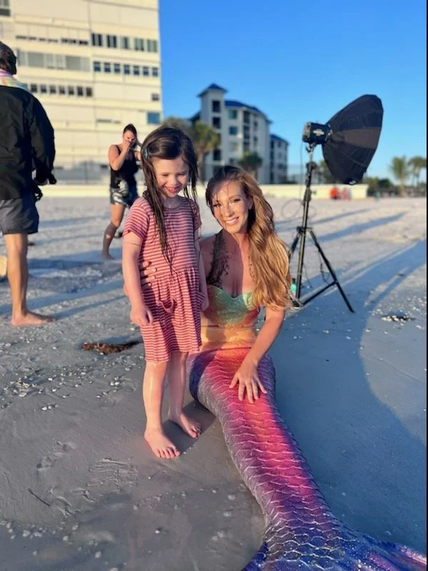professional mermaid on the beach in a silicone tail with child